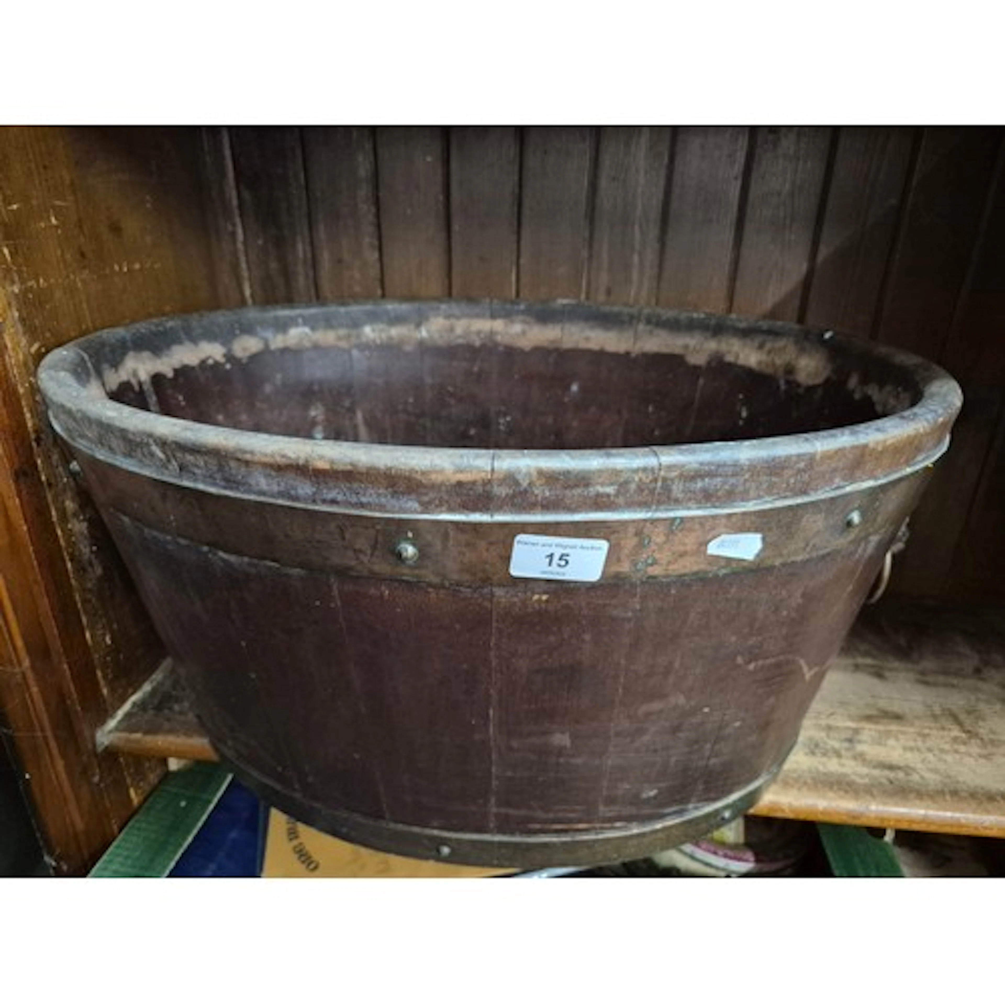 A vintage wooden oval tub with coopered staves, brass bands,...