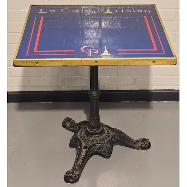 A vintage bistro table resting on heavy antique cast iron ba...