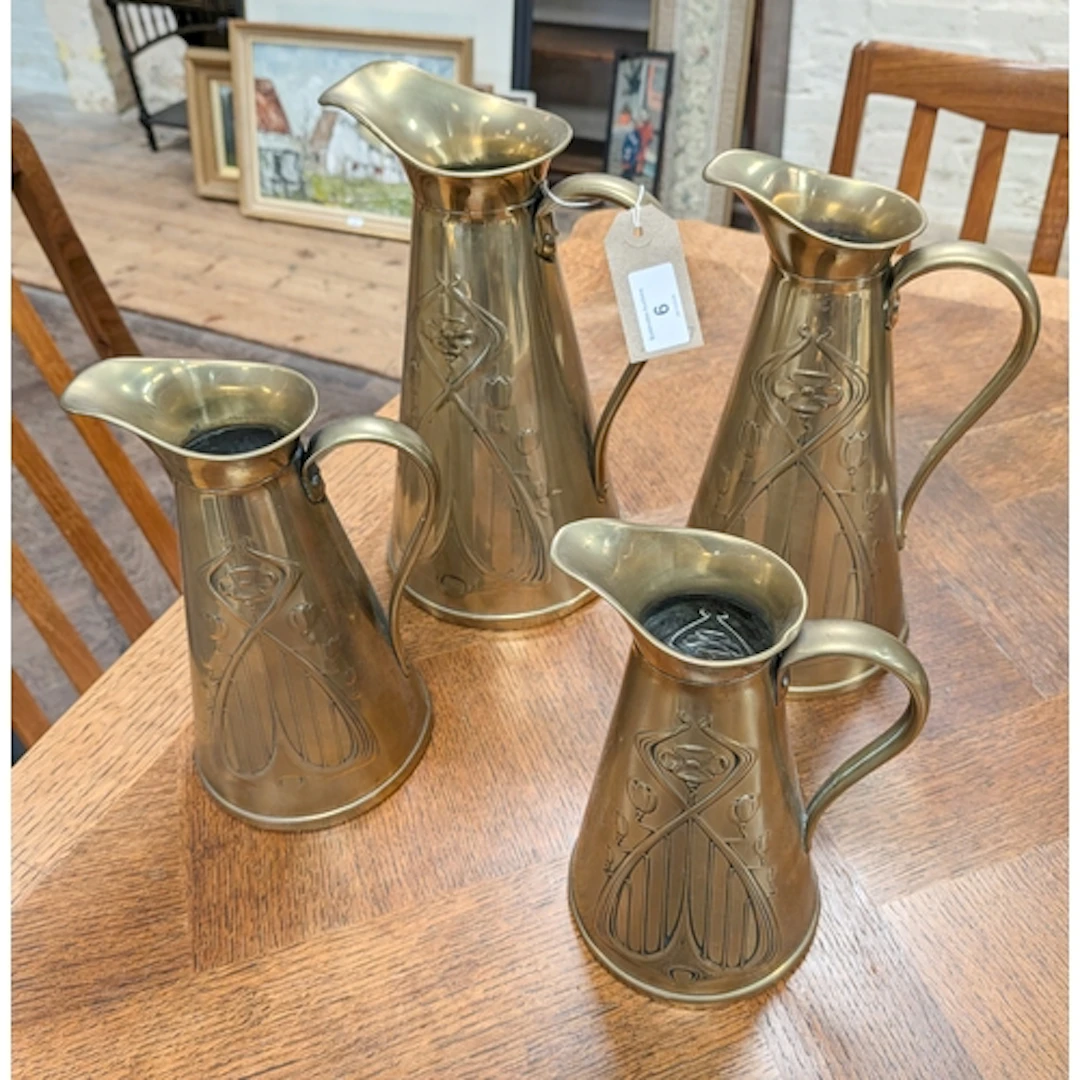 A set of four Art Nouveau graduated brass water jugs