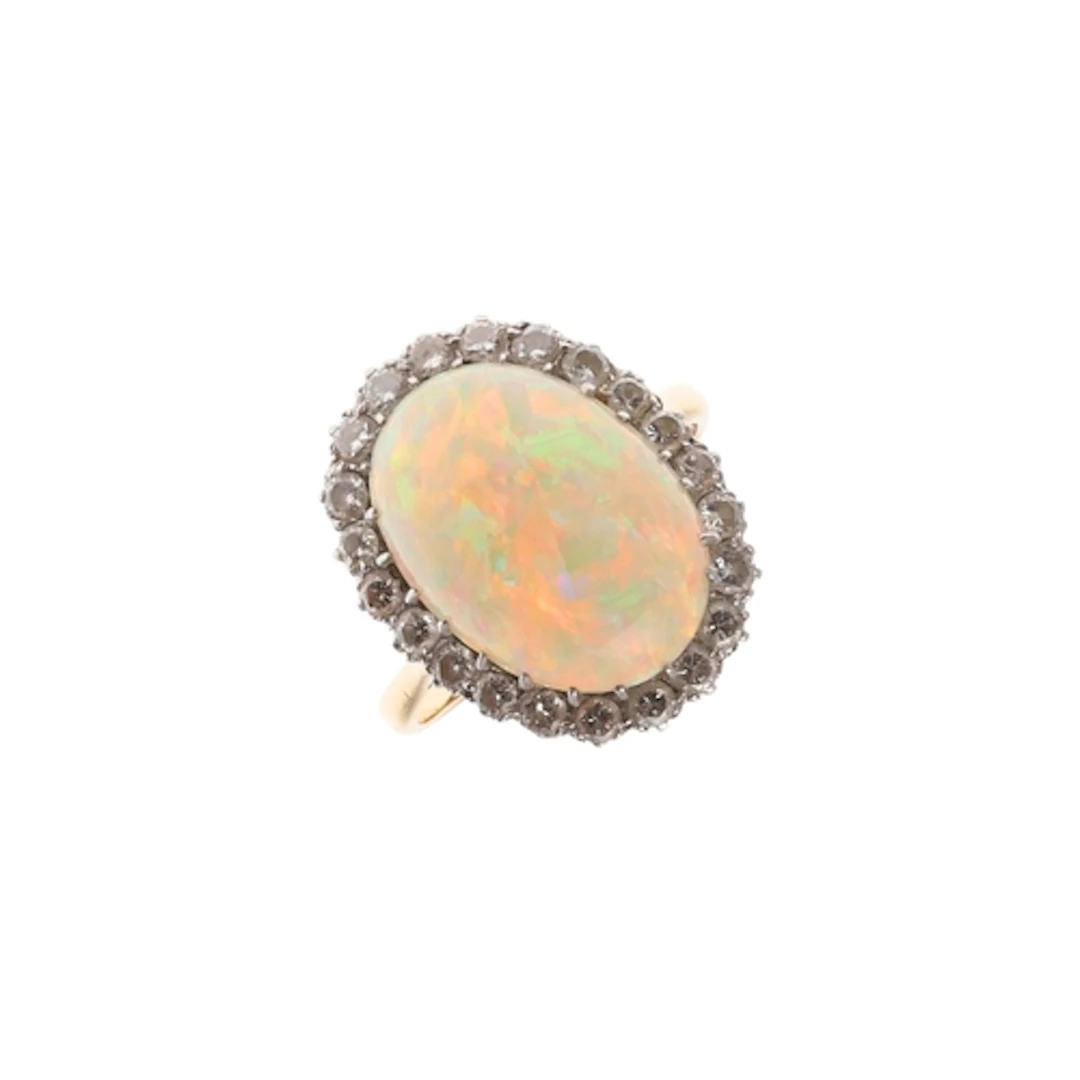 AN OPAL AND DIAMOND CLUSTER RING. the oval-shaped solid whit...