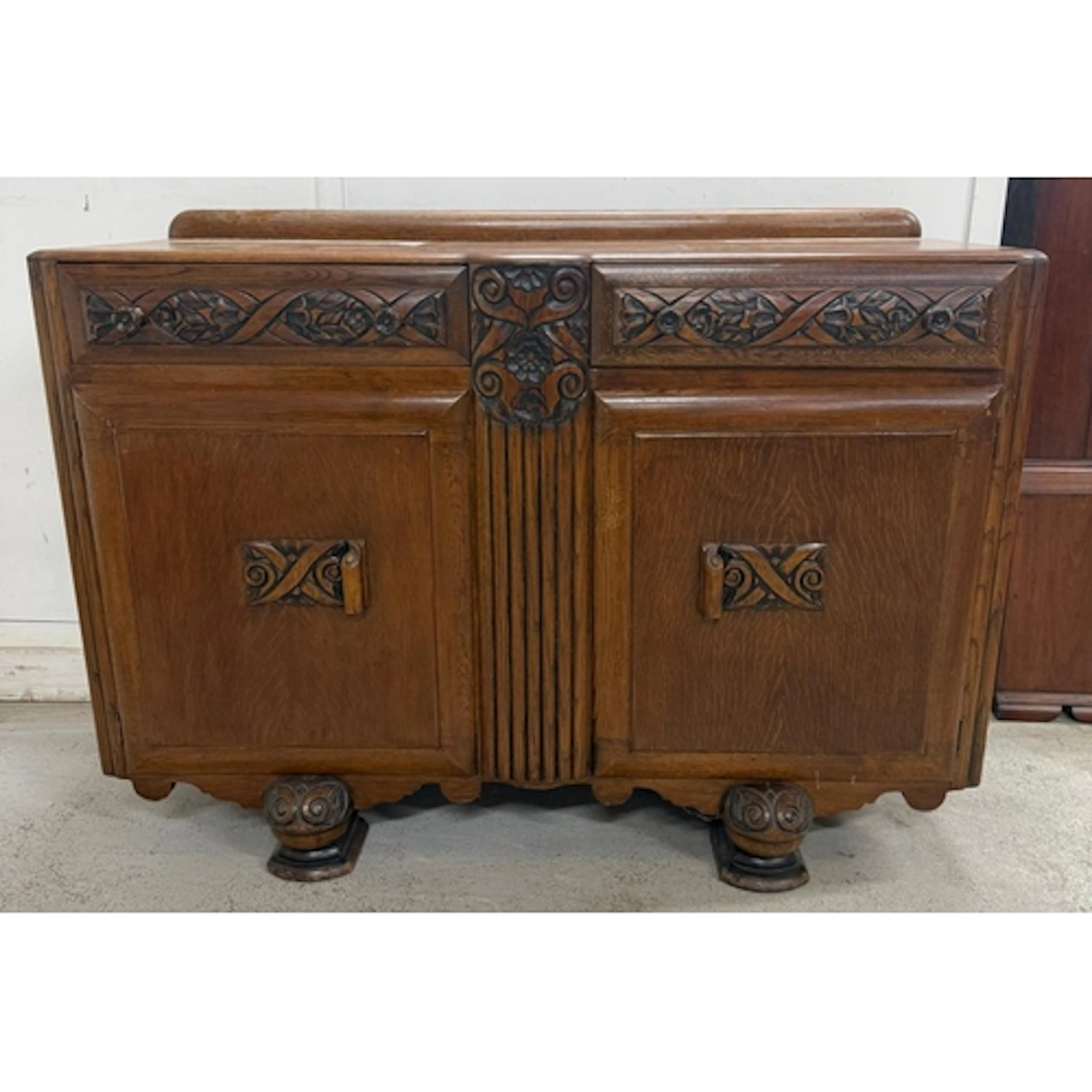 An oak art deco style buffet with two heavily carved drawers...