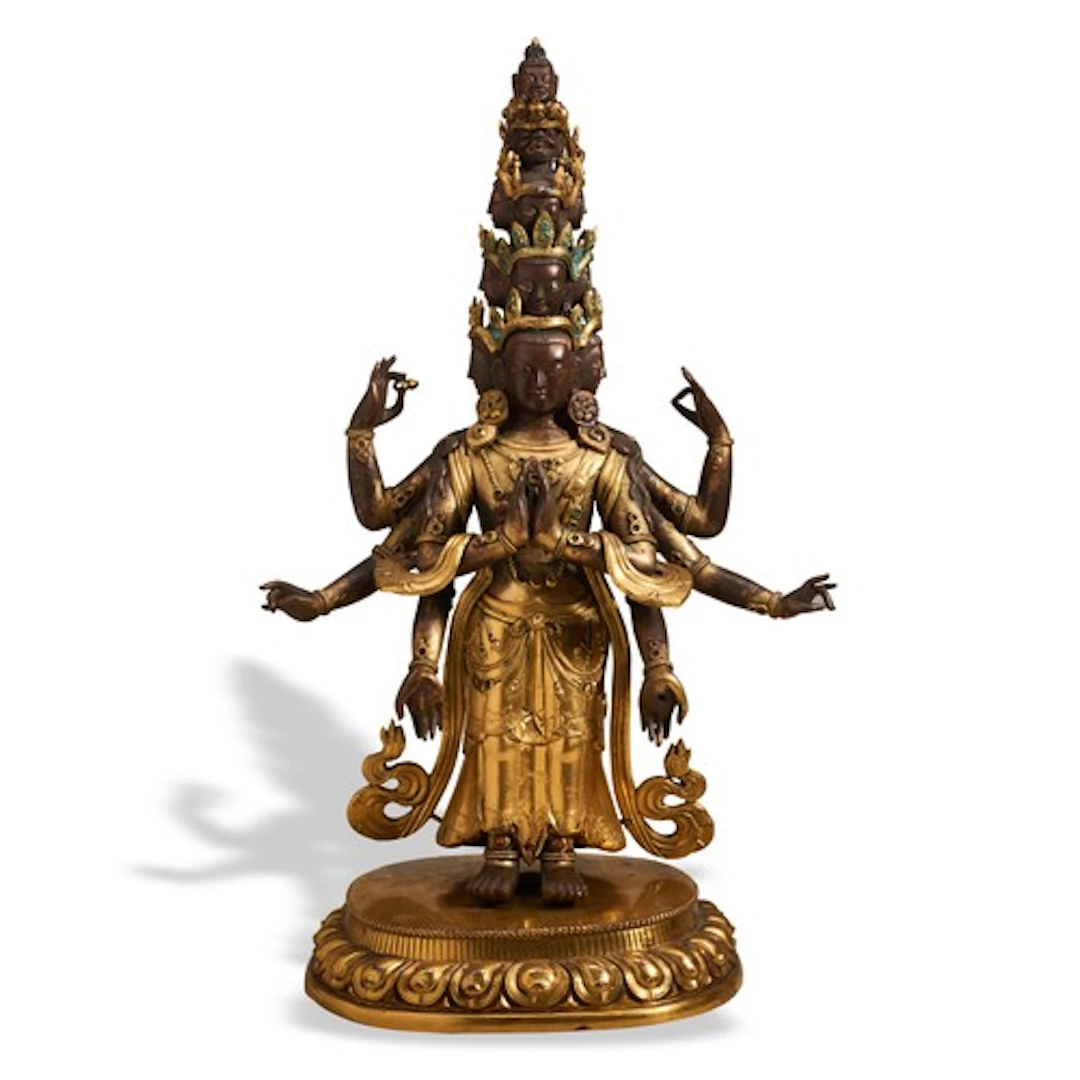 A GILT AND PATINATED BRONZE FIGURE OF ELEVEN-HEADED AVALOKIT...