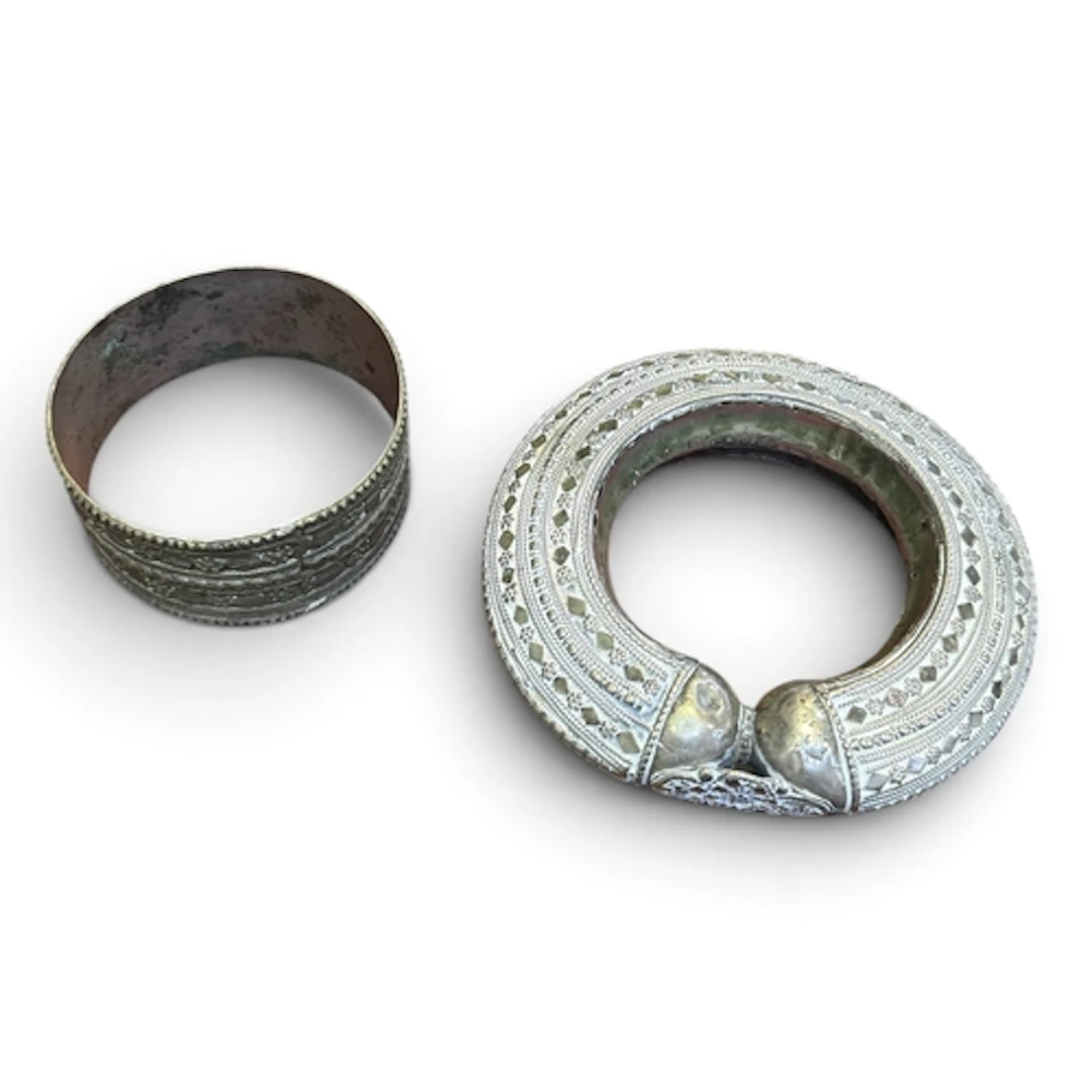 A SILVER TRIBAL BANGLE AND ANOTHER METAL BANGLE Largest 13cm...