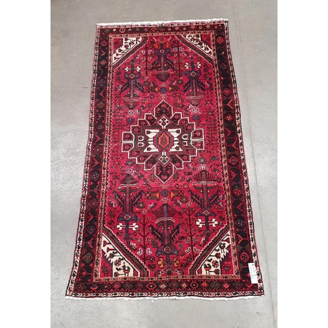 A red ground Rug with multiple borders, the centre with diam...