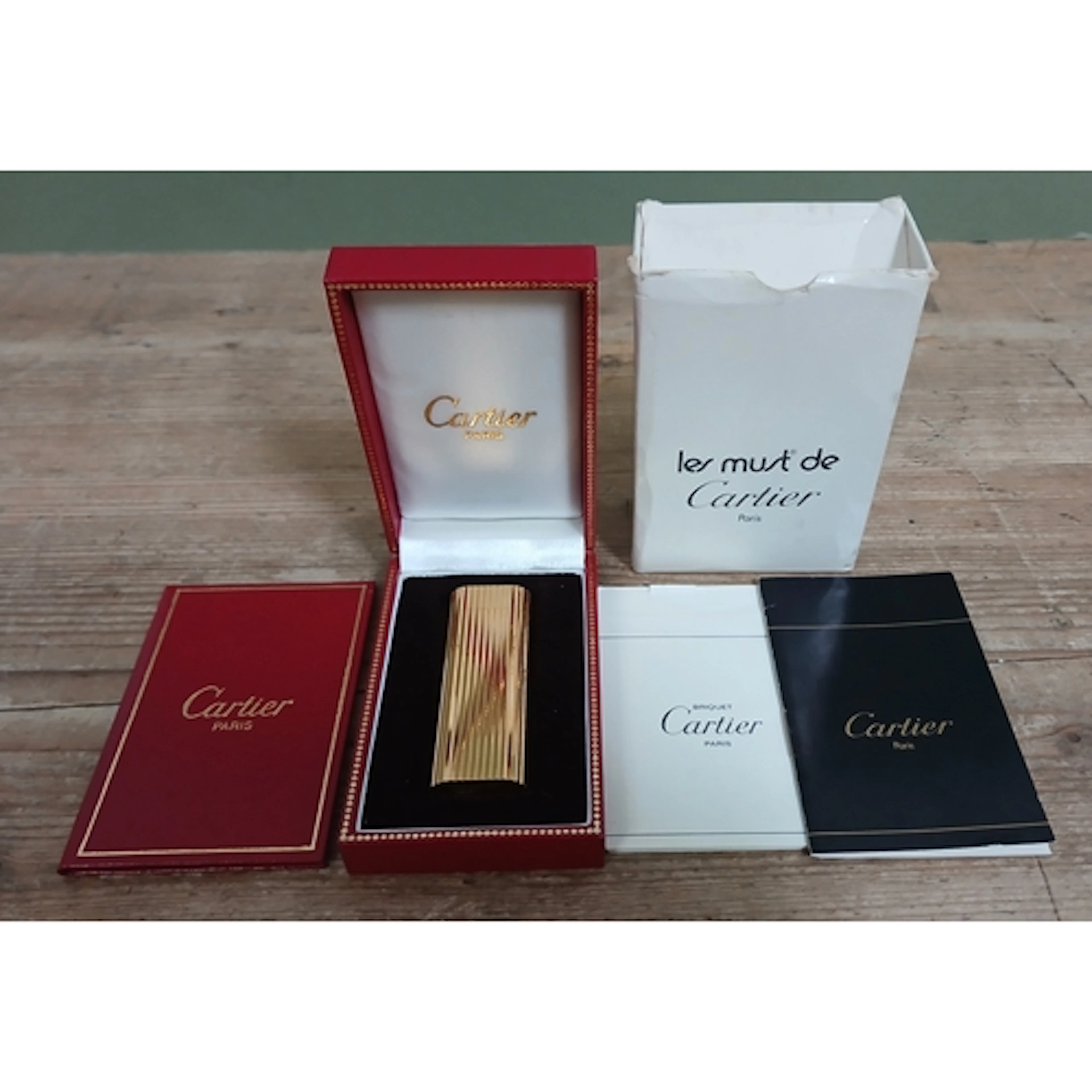 CARTIER, a gold plated lighter, with boxes and papers.