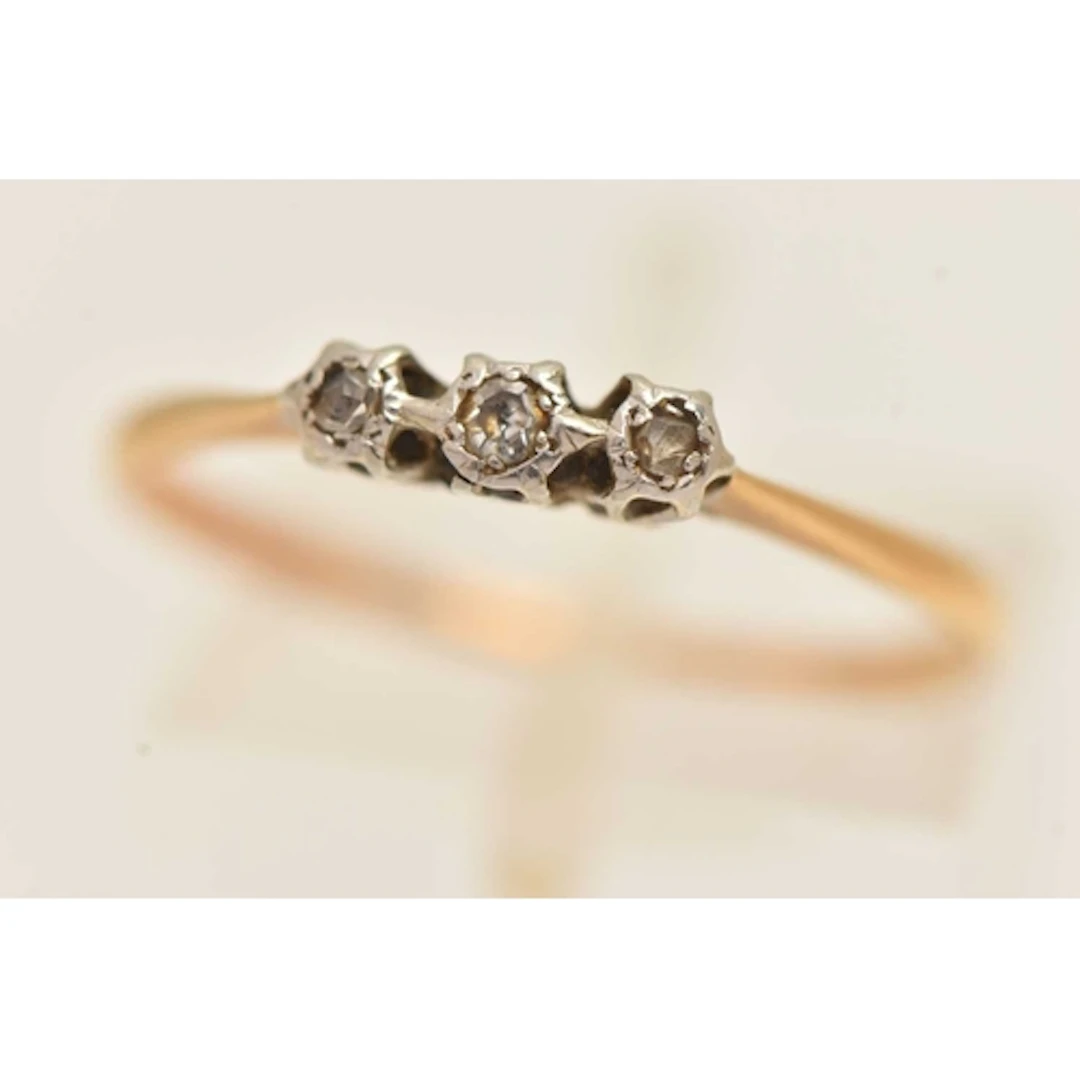 A YELLOW METAL THREE STONE DIAMOND RING, a single cut and tw...