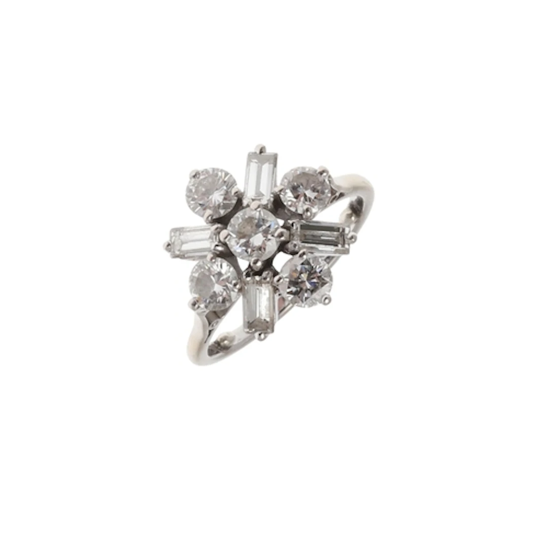 A DIAMOND CLUSTER RING. the central brilliant-cut diamond is...