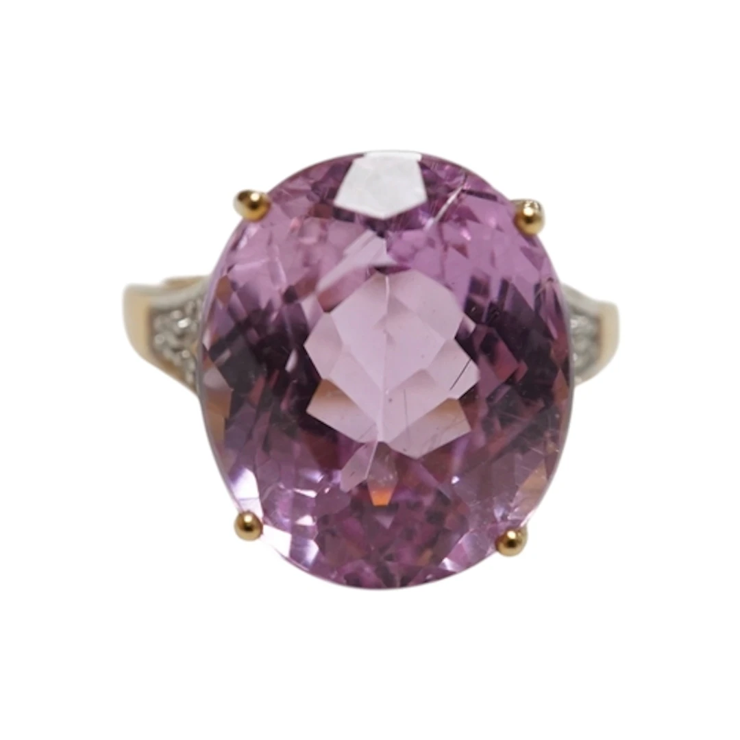 A kunzite and diamond ring, claw-set with an oval kunzite we...