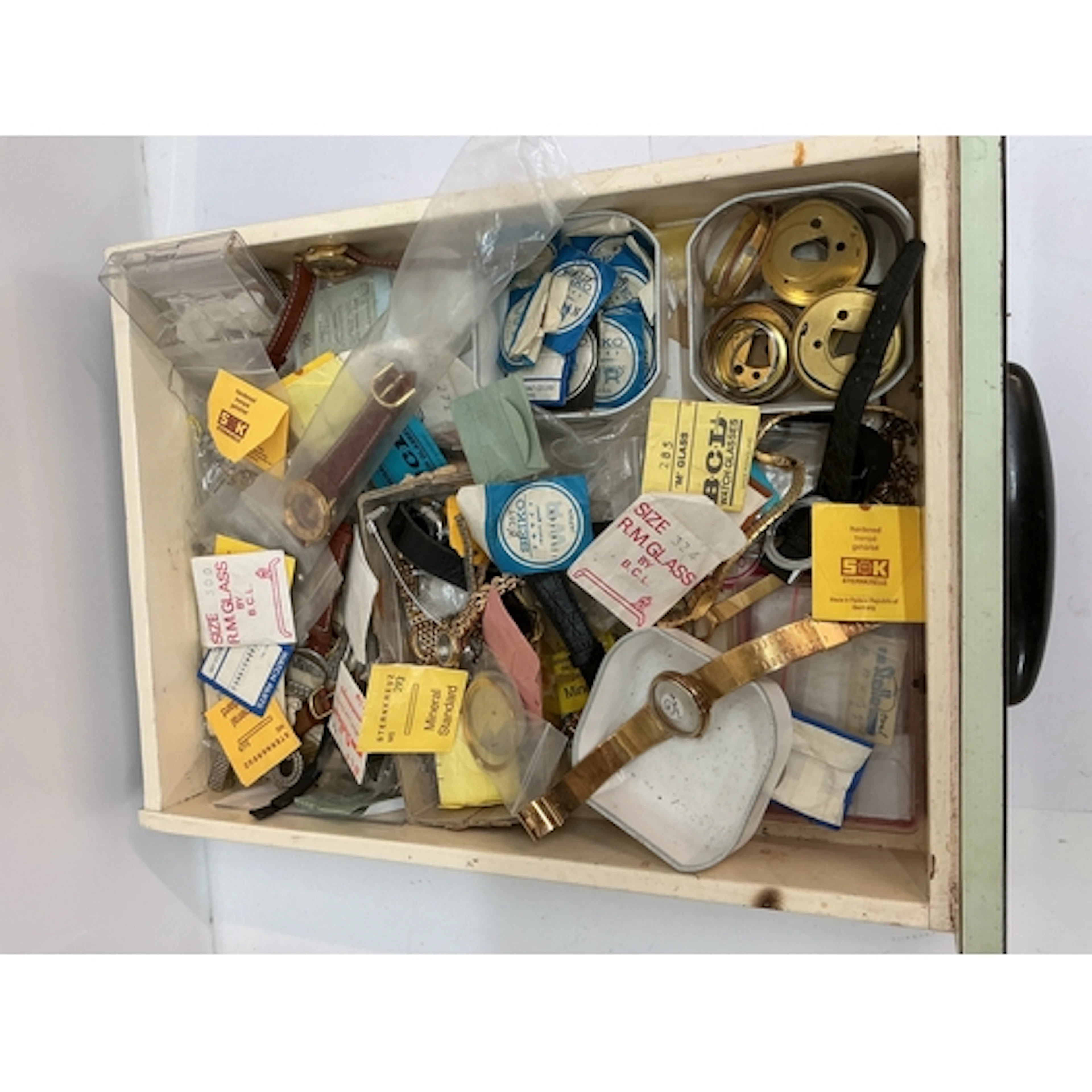 A tray containing assorted watch parts and fittings
