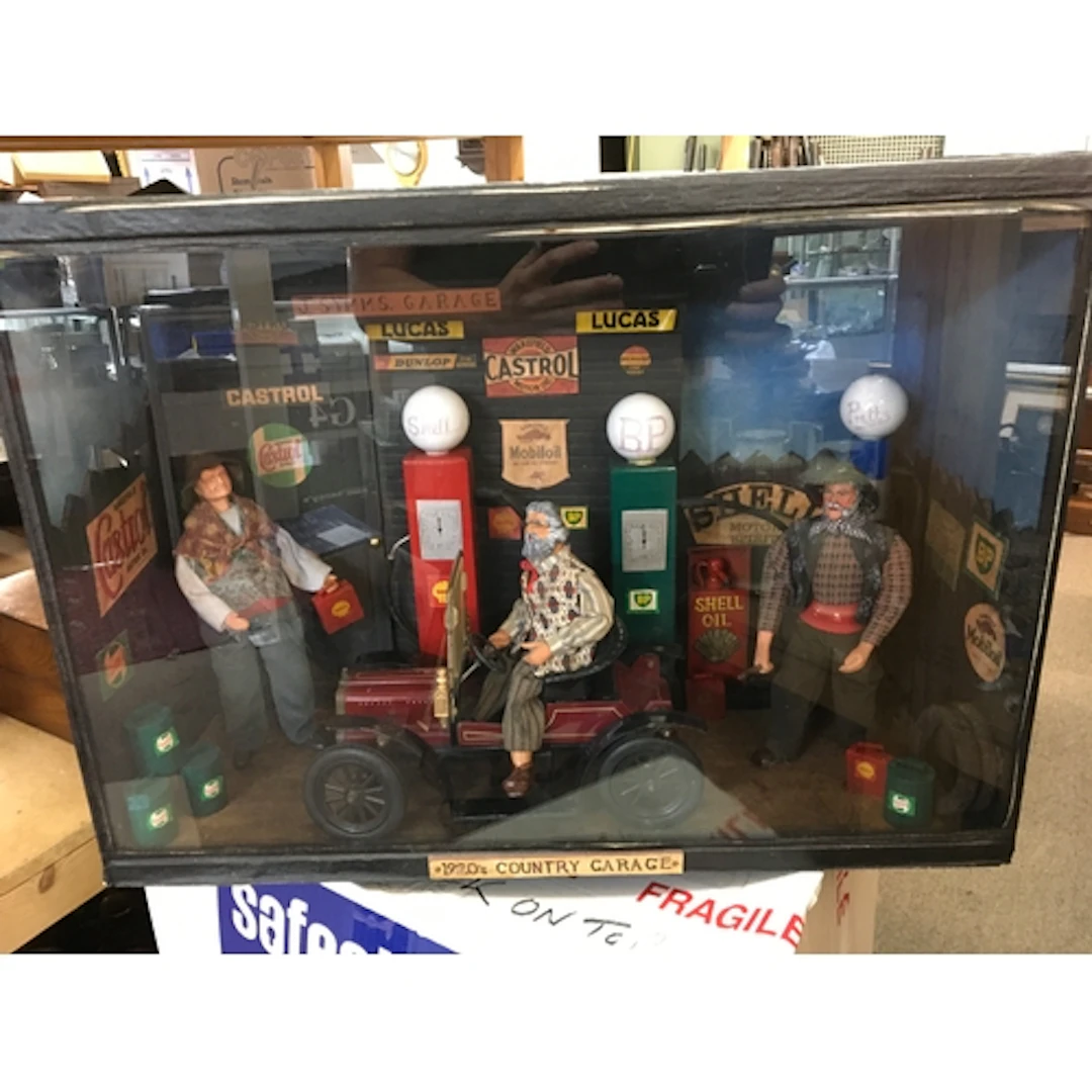A diorama of a 1920s village garage with pumps, oil and petr...