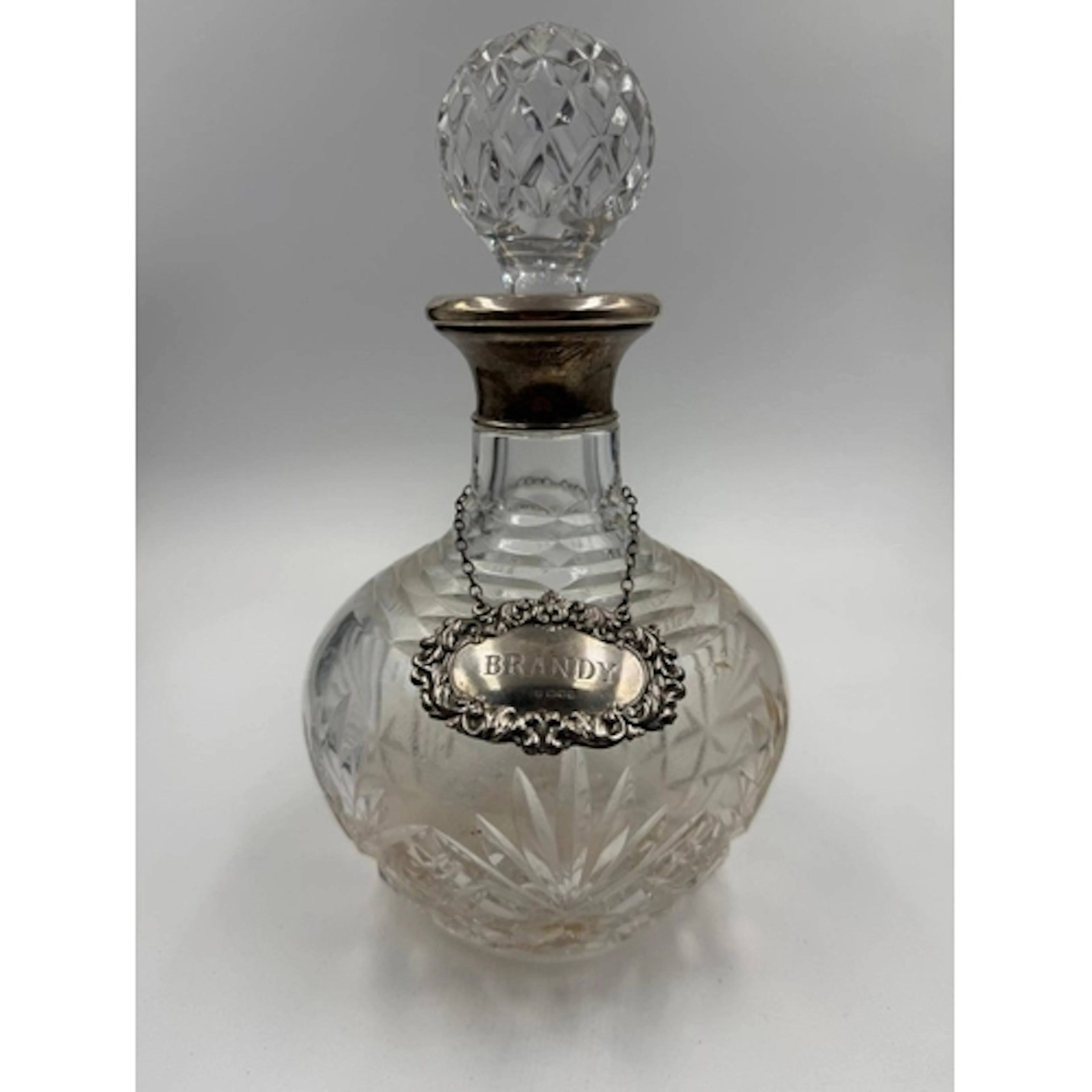 A cut glass decanter with a silver hallmarked collar and Bra...