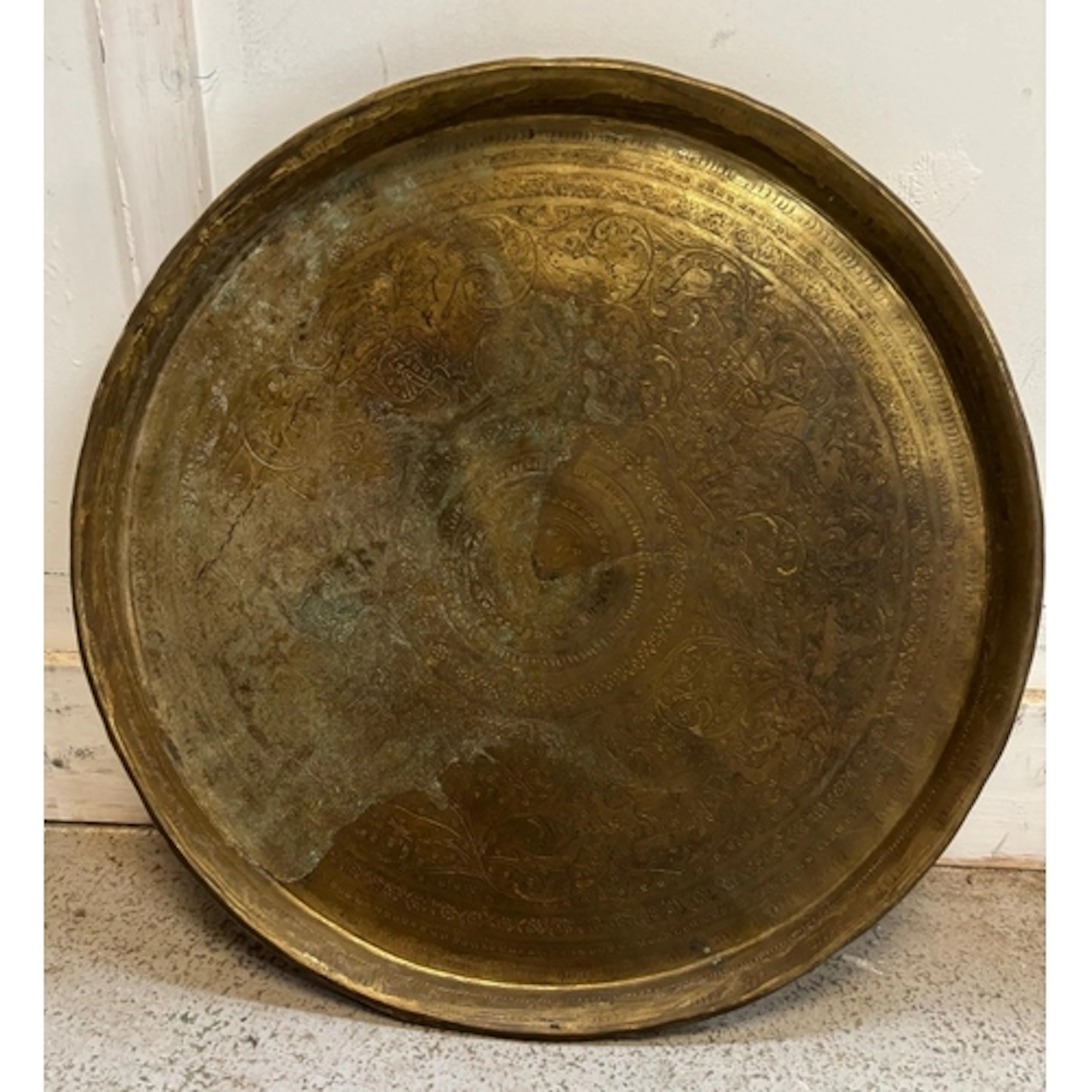 A vintage round brass tray featuring a warm weathered patina...