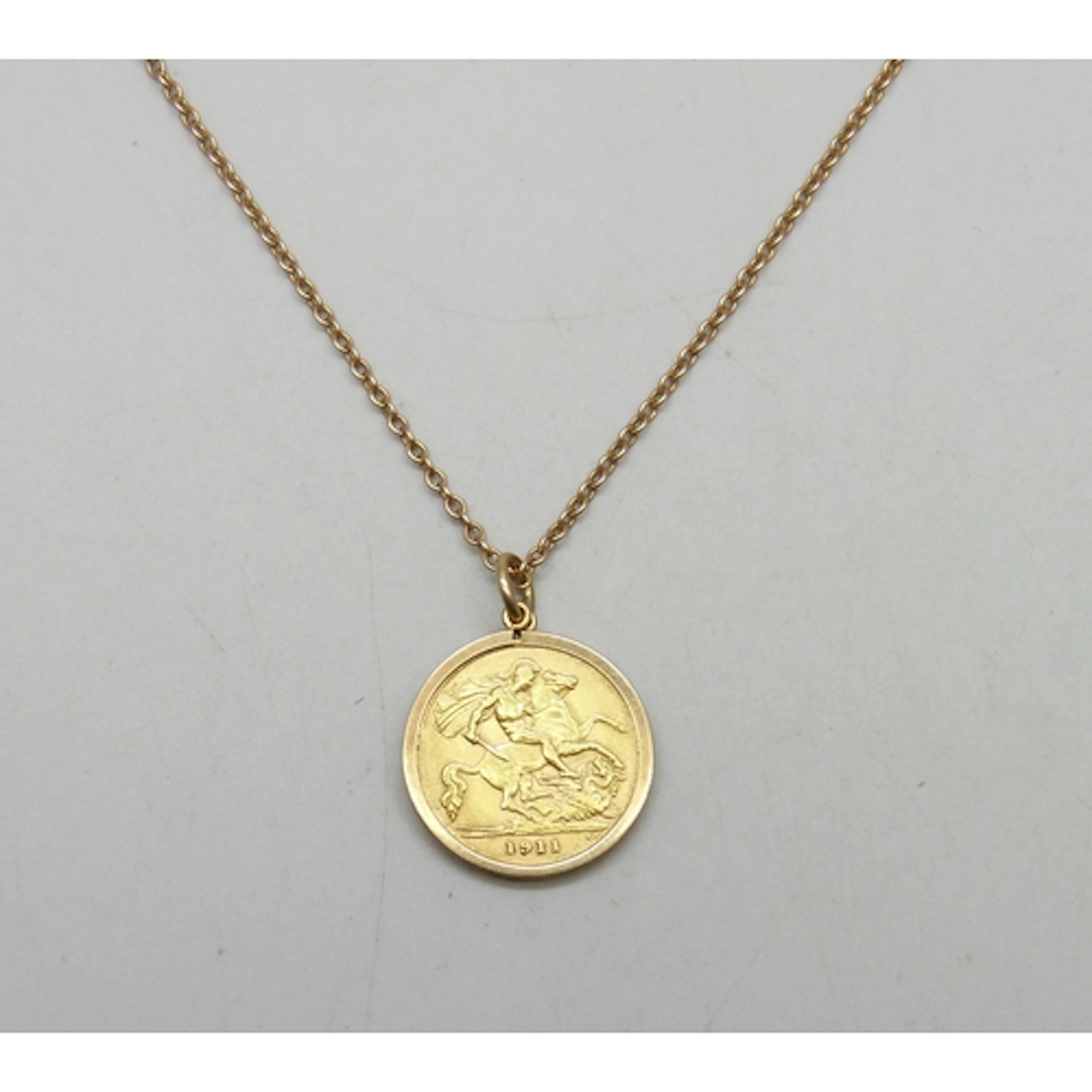 A George V 1911 gold half sovereign in a 9ct gold pendant mo...