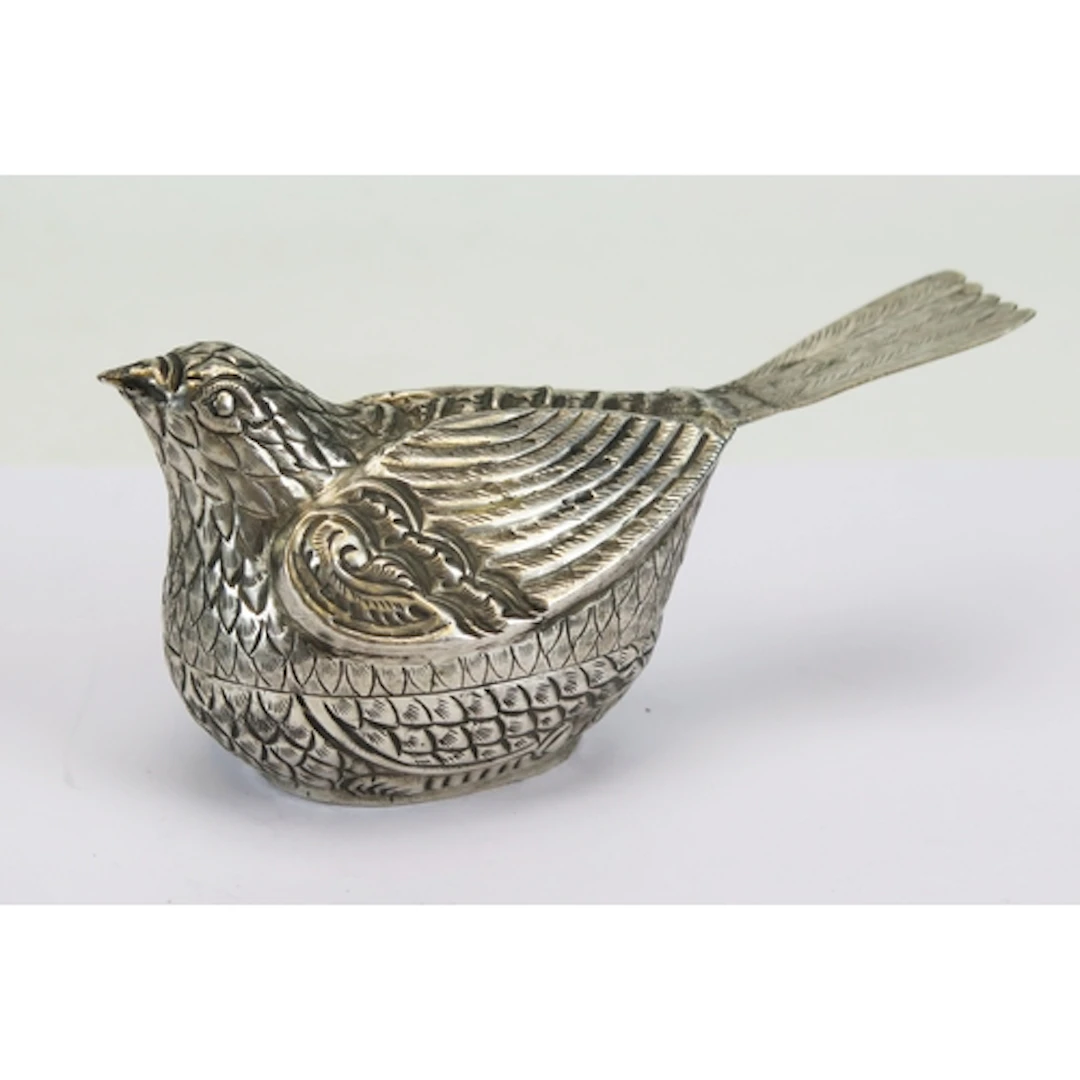 A white metal box in the form of a bird with repousse and ch...