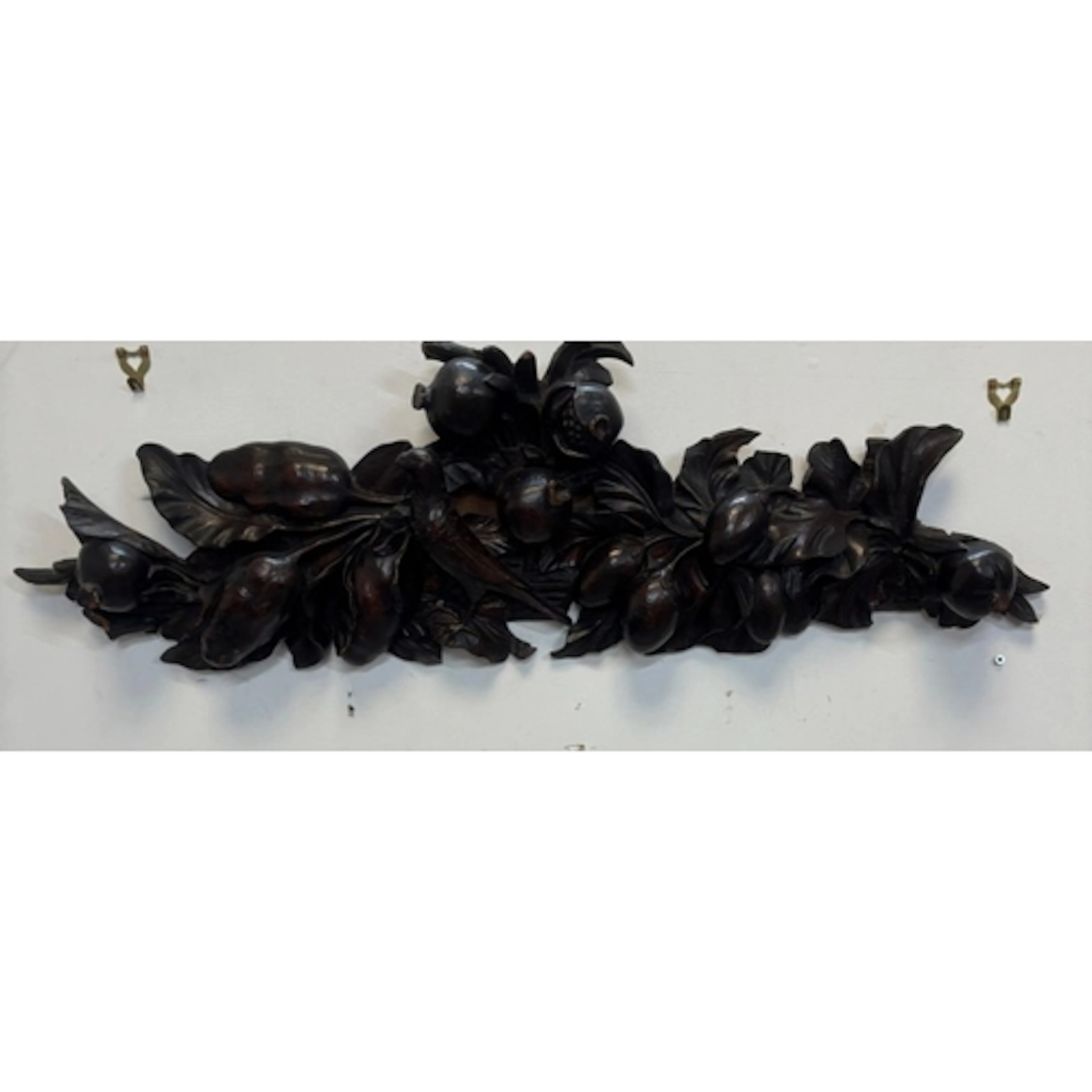 A dark stained wood carving featuring a deeply sculpted frui...