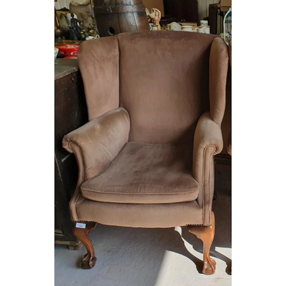 A large brown upholstered wingback Armchair raised on cabrio...