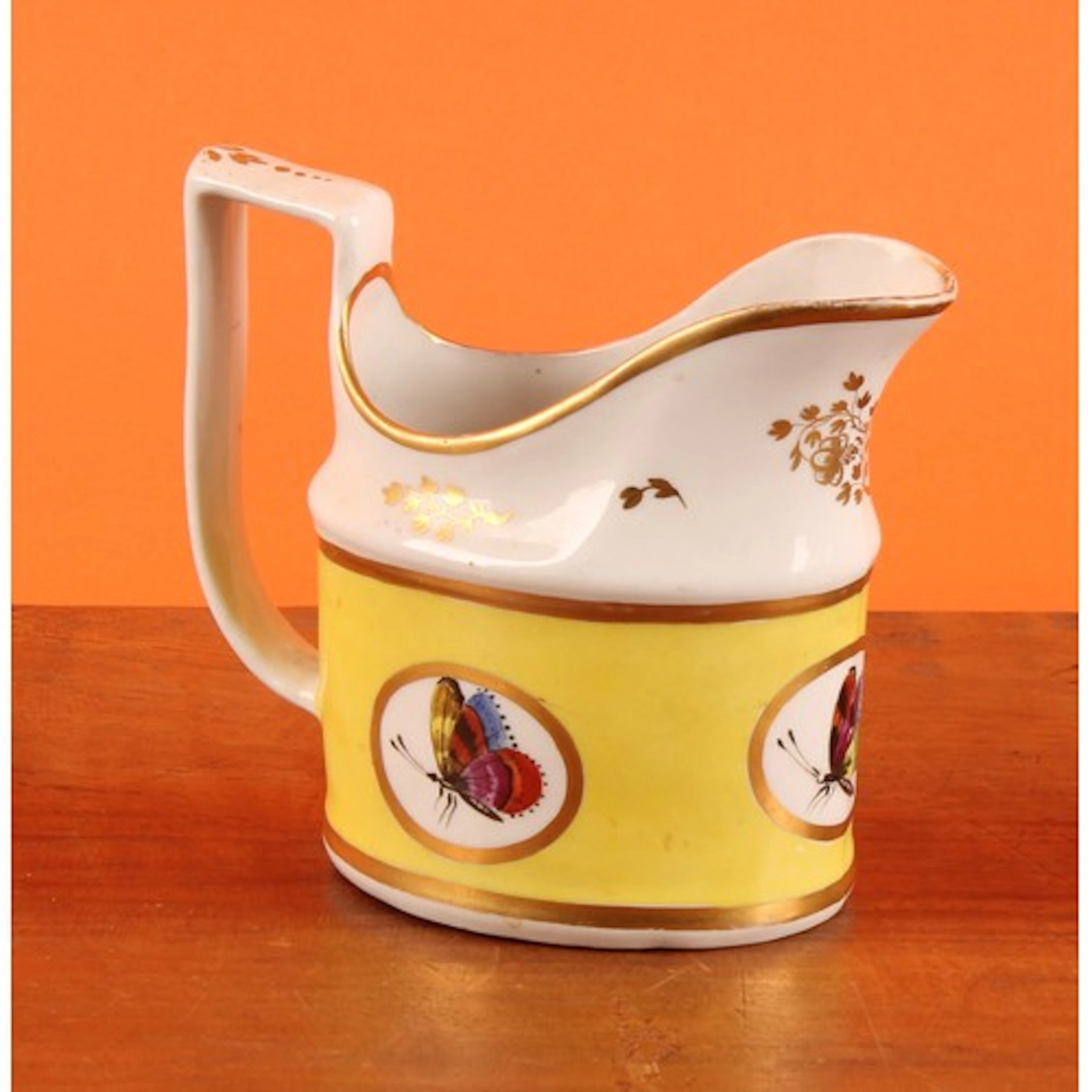 A New Hall cream jug, painted with butterflies, within three...