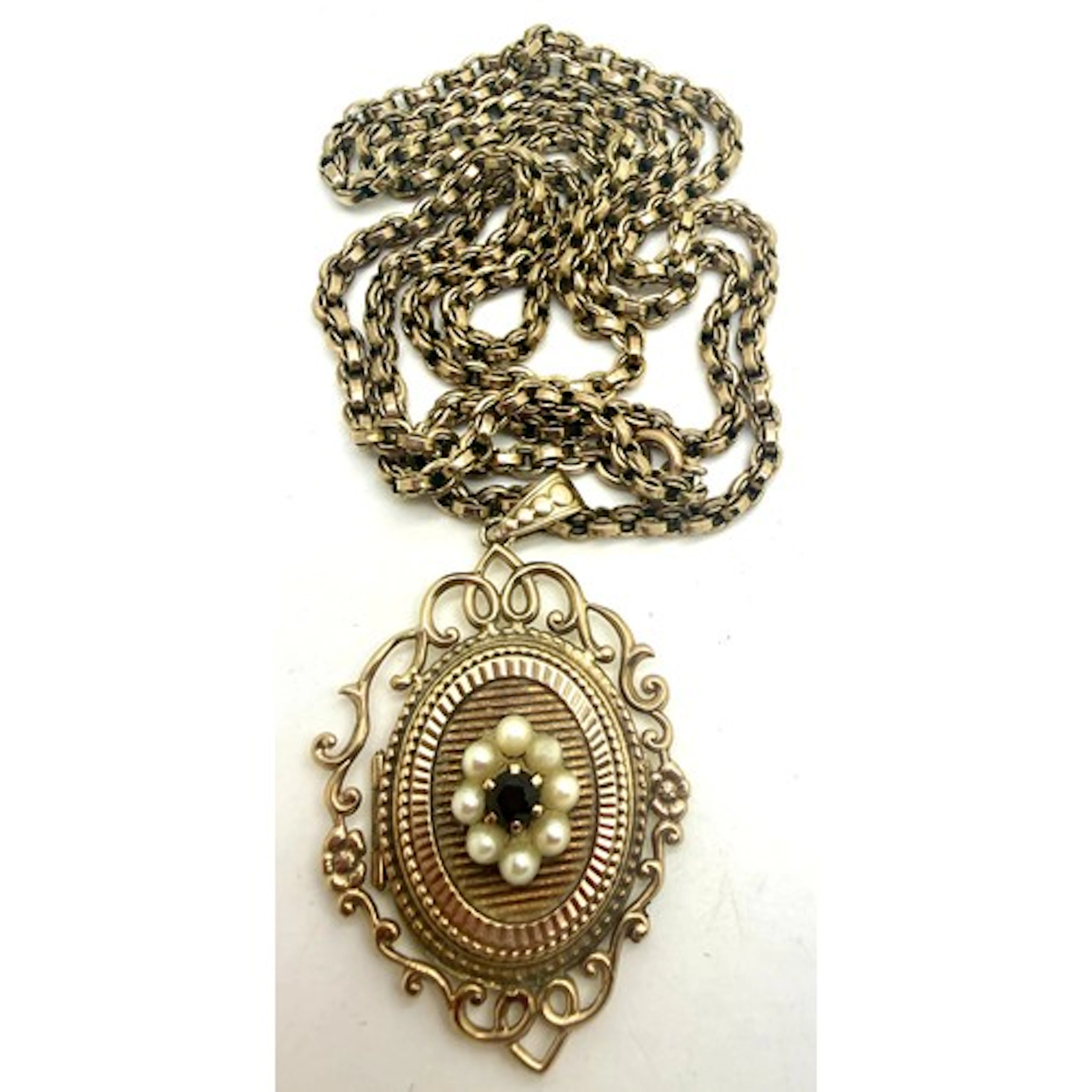 A 9 carat gold locket set with seed pearls and garnet, suspe...