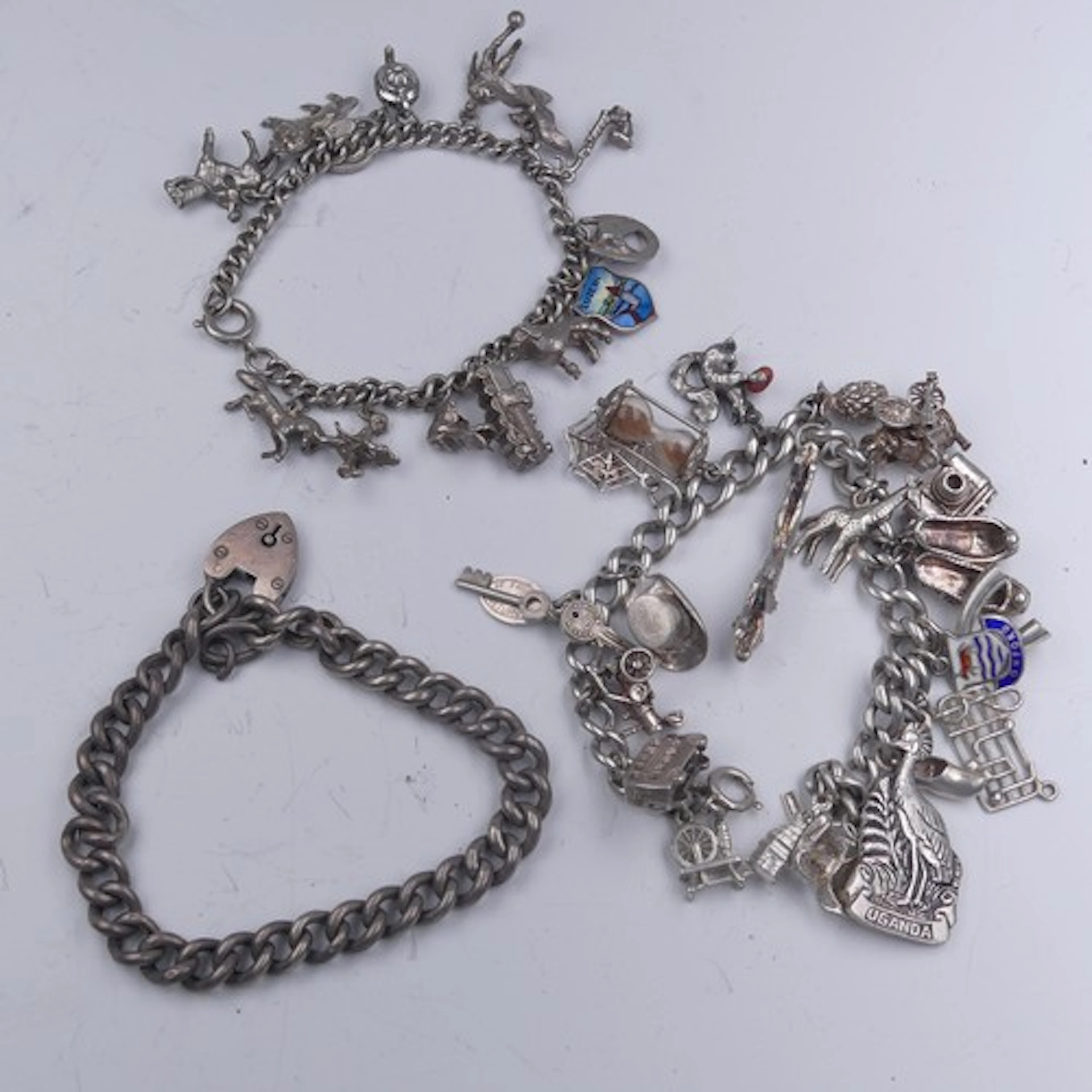 A silver Charm Bracelet, with bolt ring clasp, suspending 21...