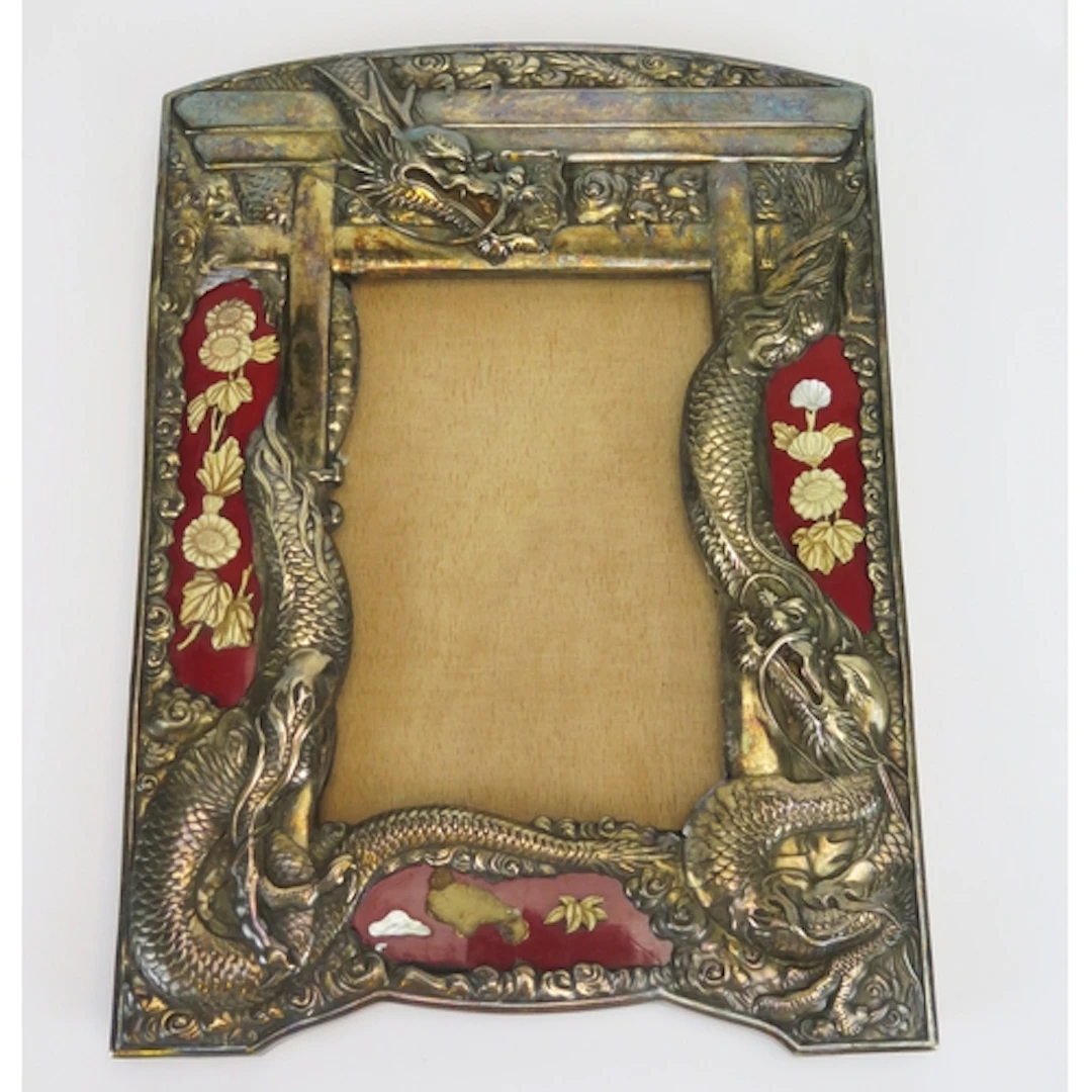 A Chinese white metal frame with embossed dragon decoration ...