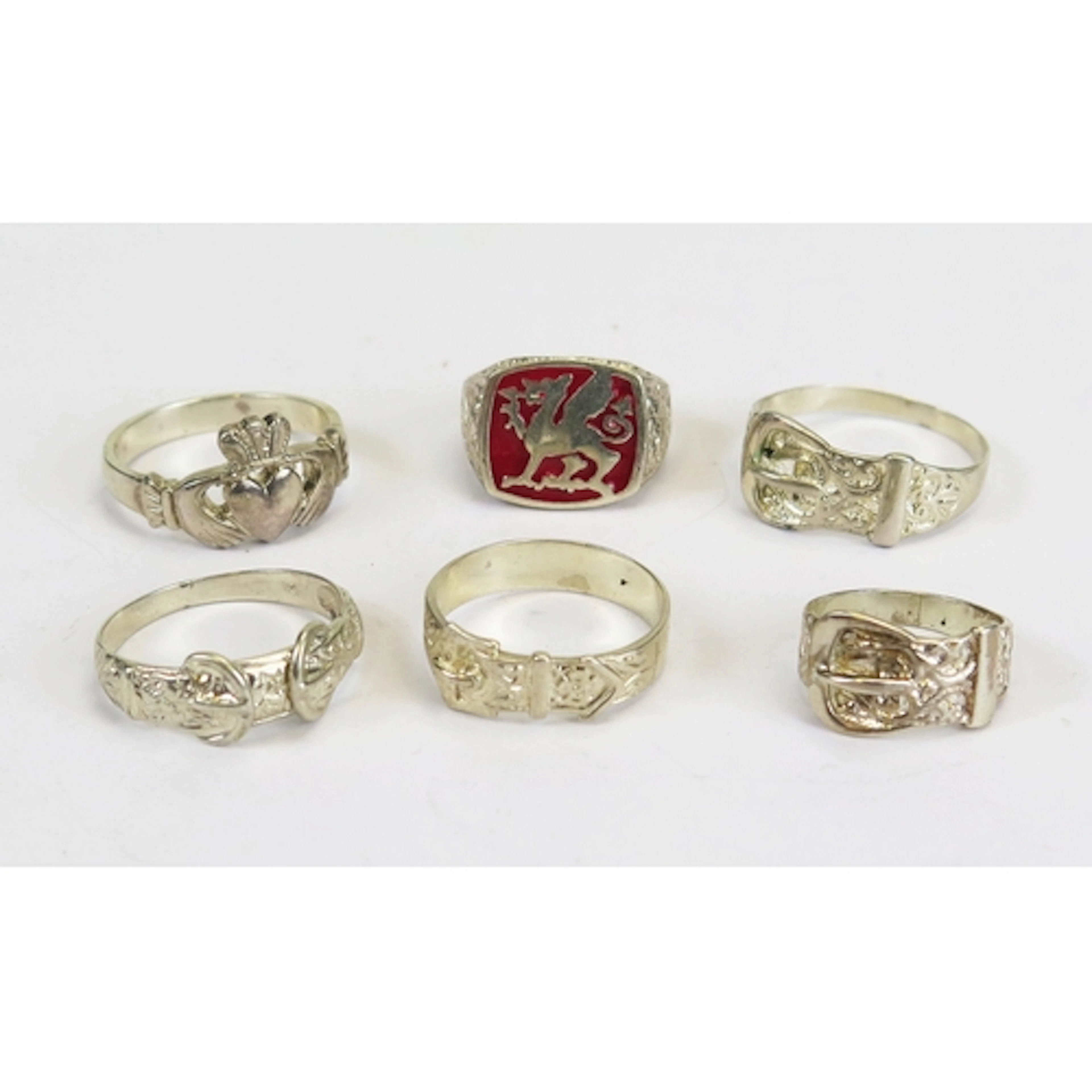 Six silver rings including Claddagh, buckle and Welsh dragon...