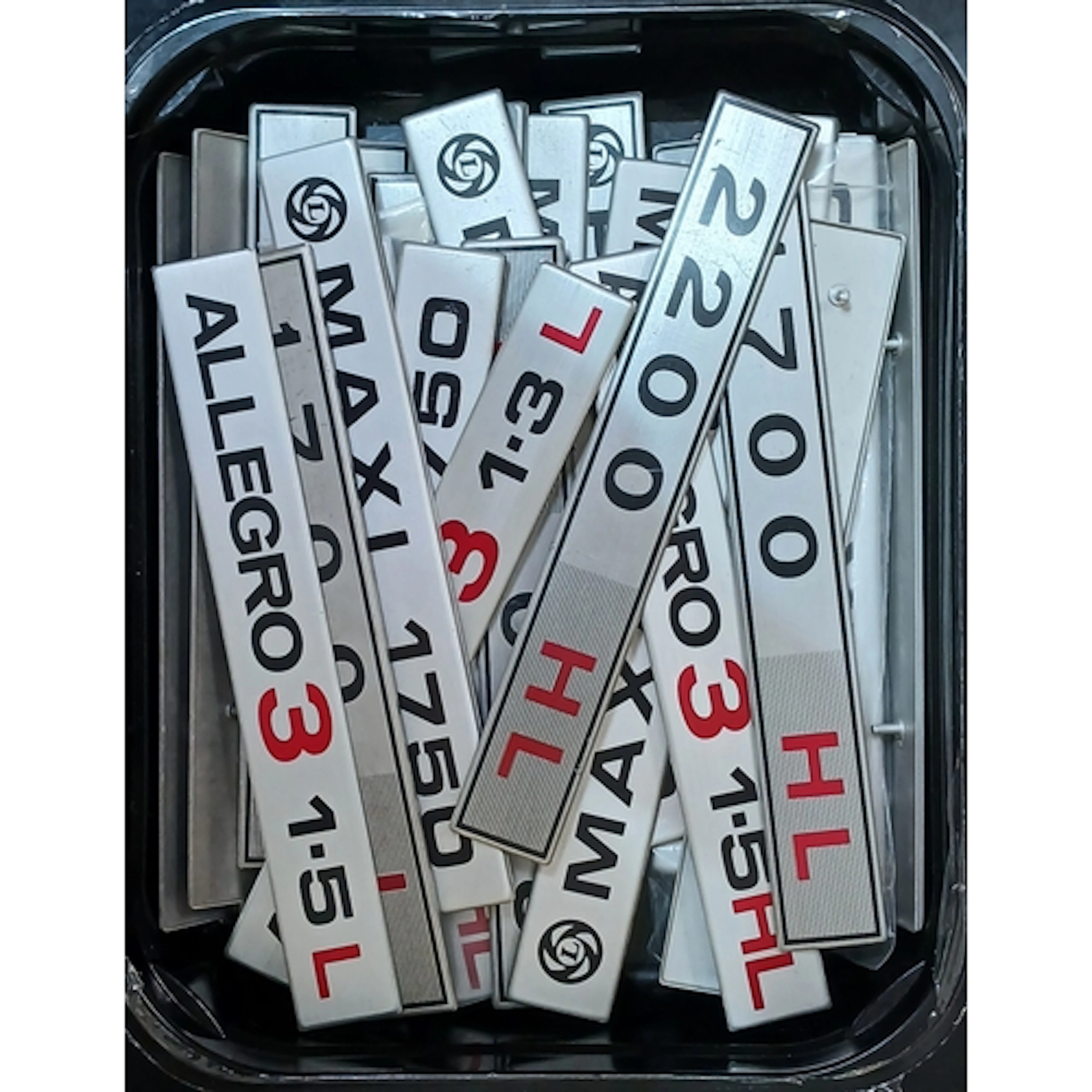 A box of assorted classic car badges.