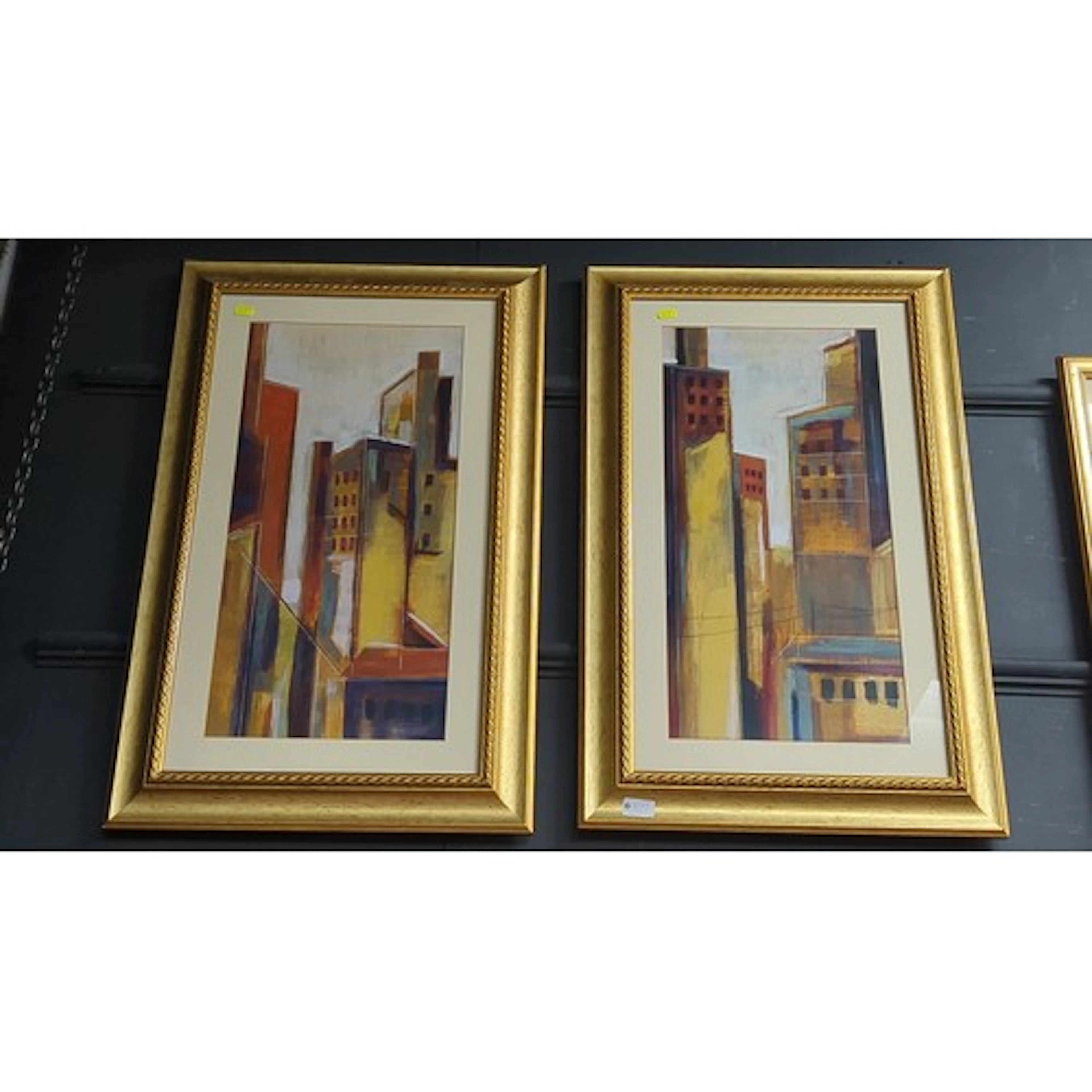 A pair of framed abstract cityscape prints in warm ochre and...
