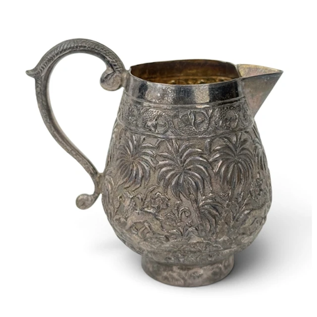 AN INDIAN SILVER CREAM JUG Decorated in Repousse with palm t...
