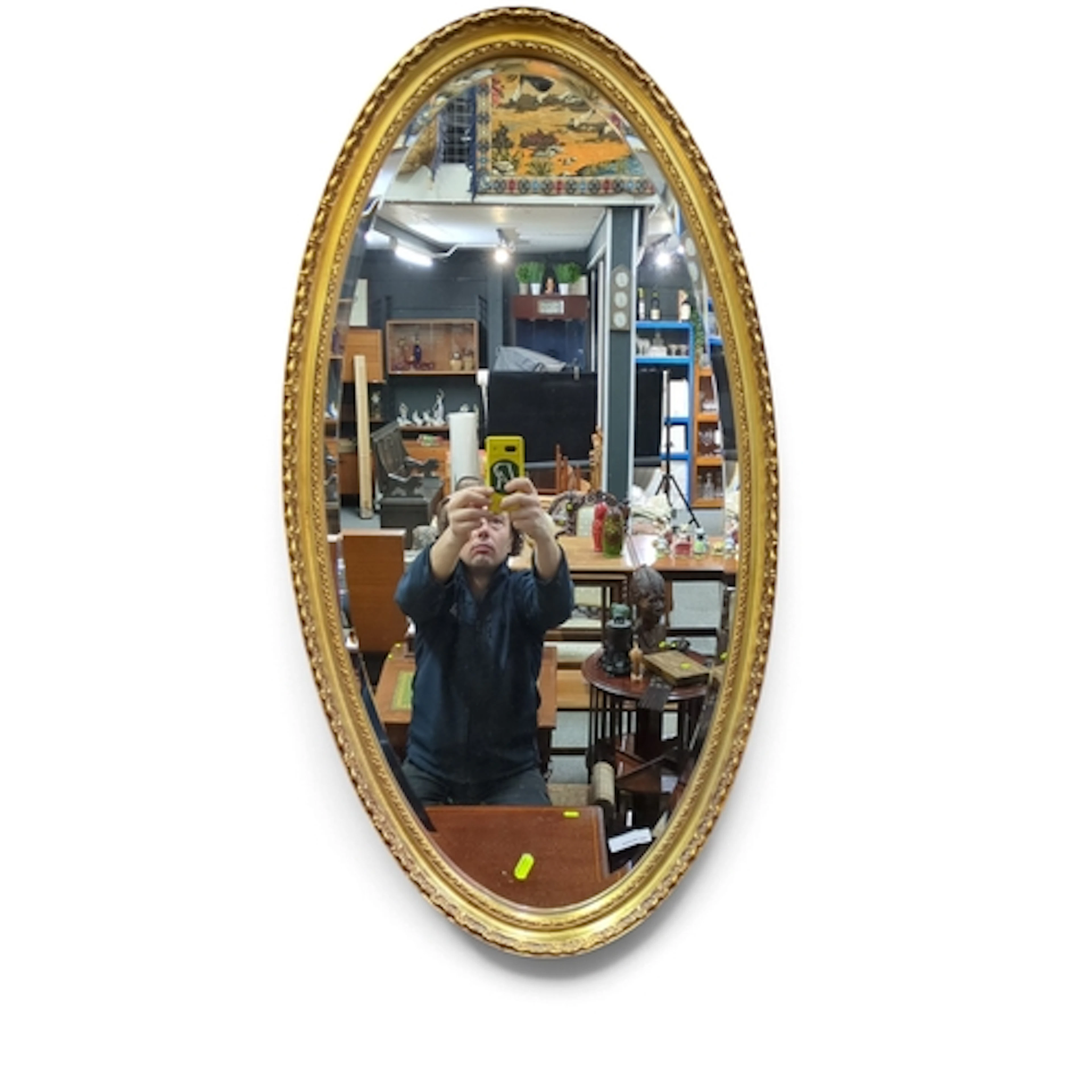 Oval wall mirror with bevelled plate in a gilt frame, the mo...