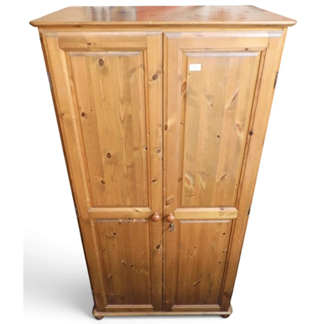 A 20th century pine two door wardrobe with turned handles on...