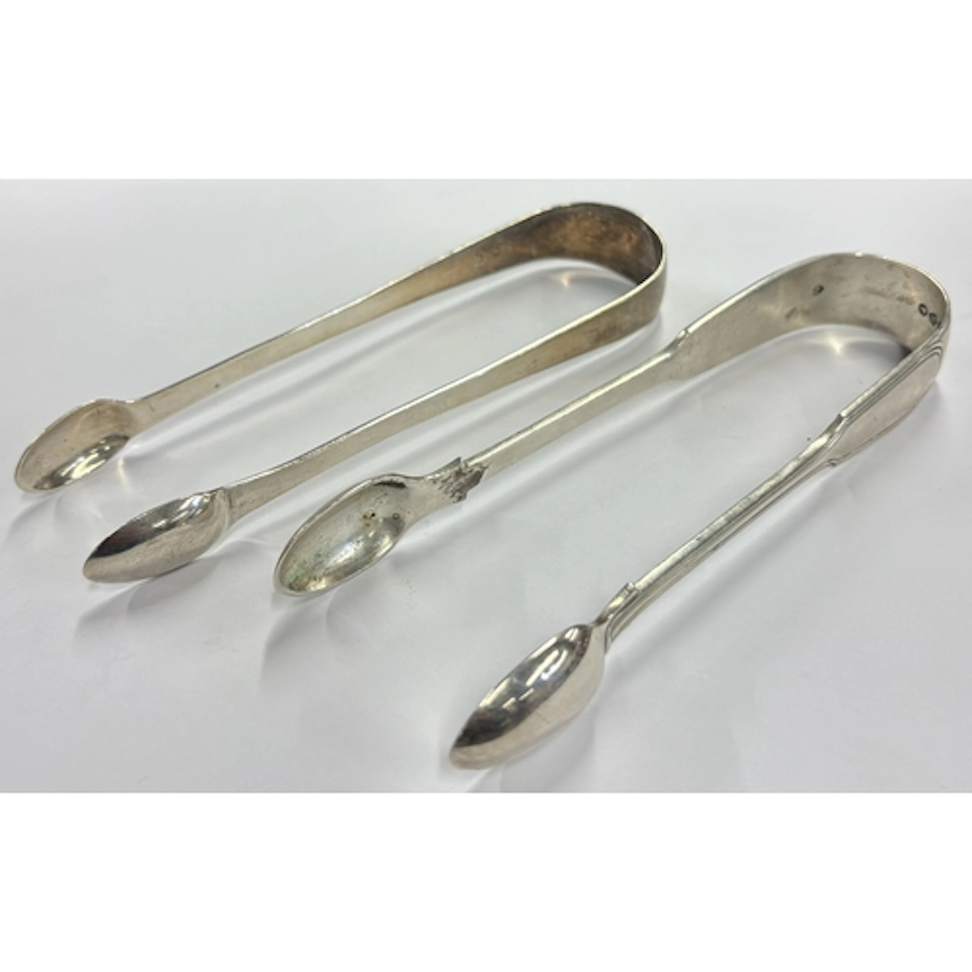 A pair of Georgian silver fiddle pattern tongs together with...
