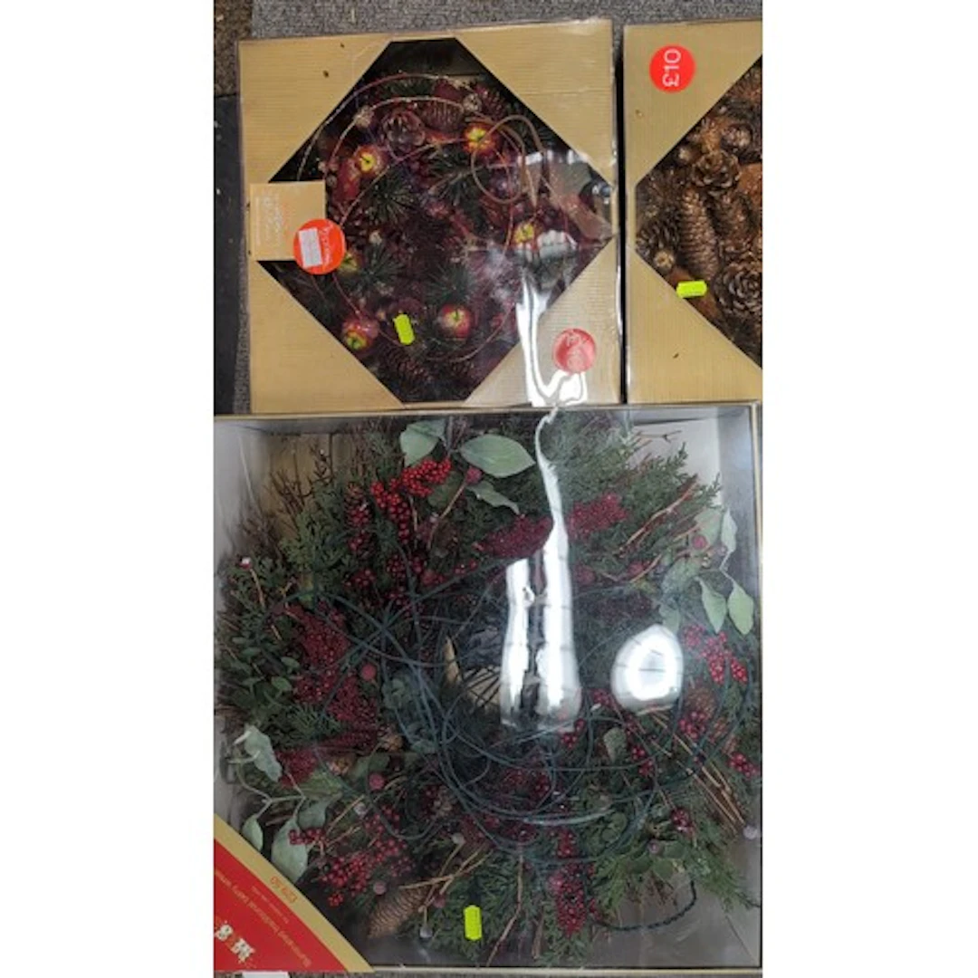 Three boxed decorative Christmas wreaths: one with faux ever...