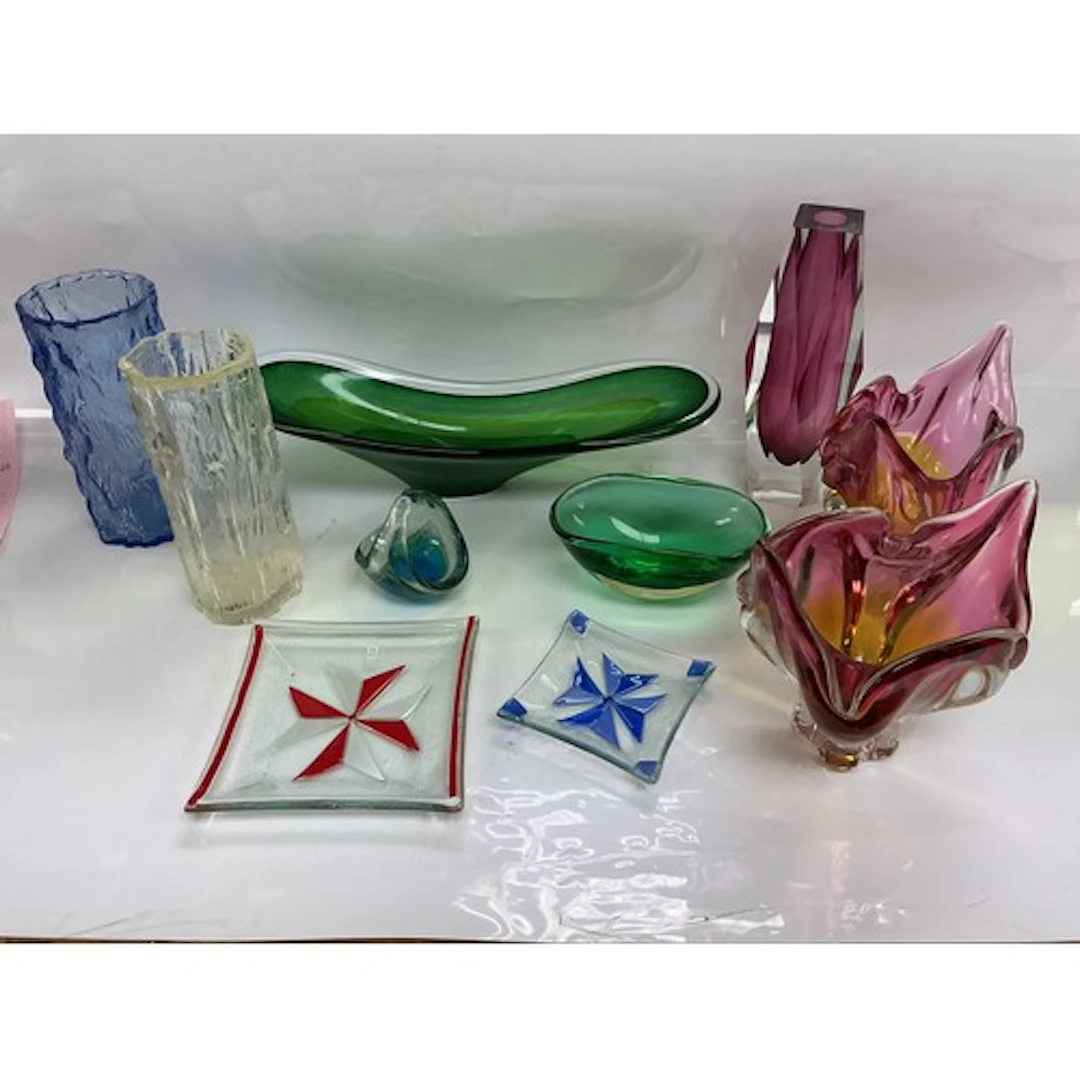A collection of coloured glassware including Mdina examples.