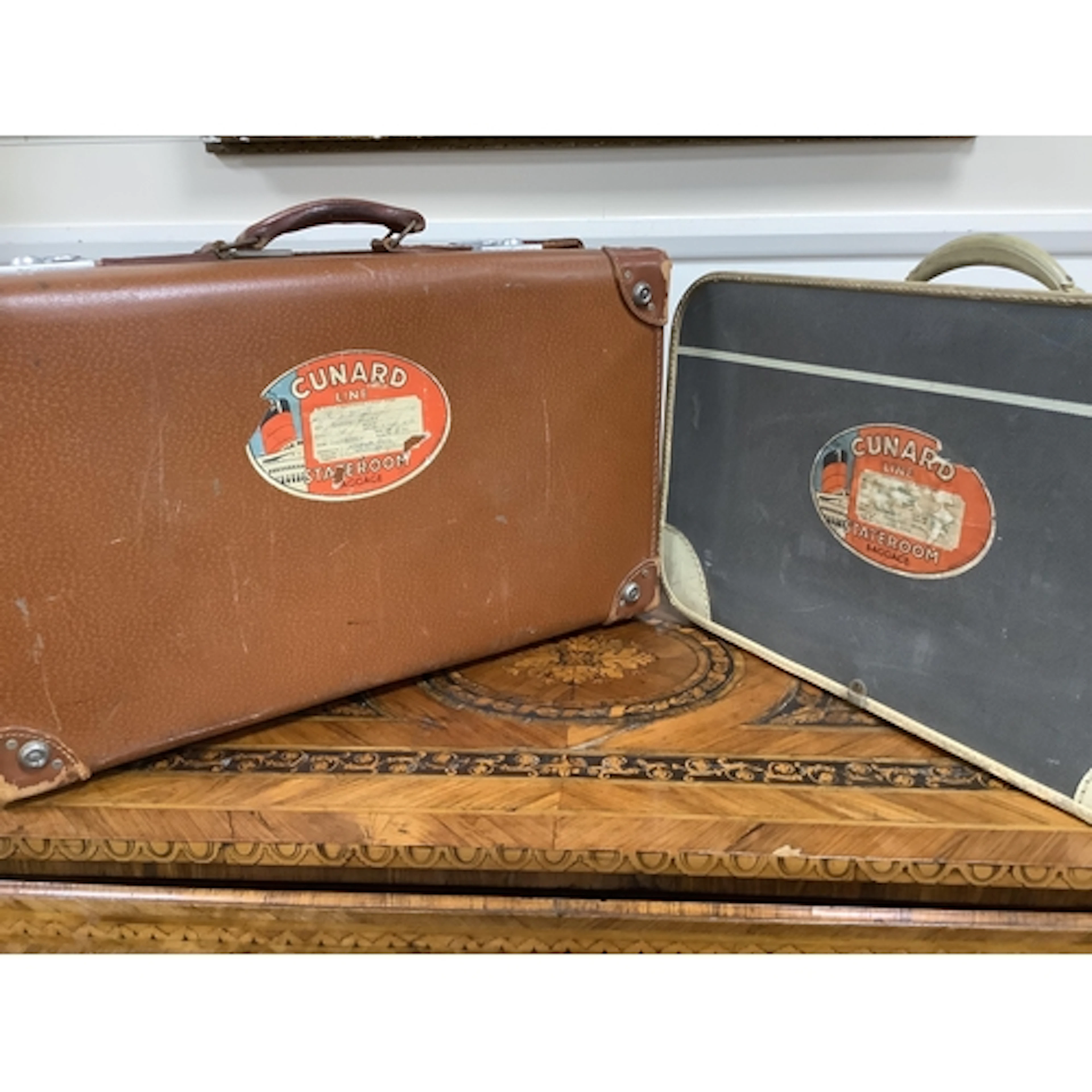 Two vintage suitcases with Cunard labels. The labels read; 1...