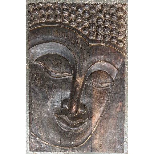 A large relief carved wall plaque depicting the face of Budd...
