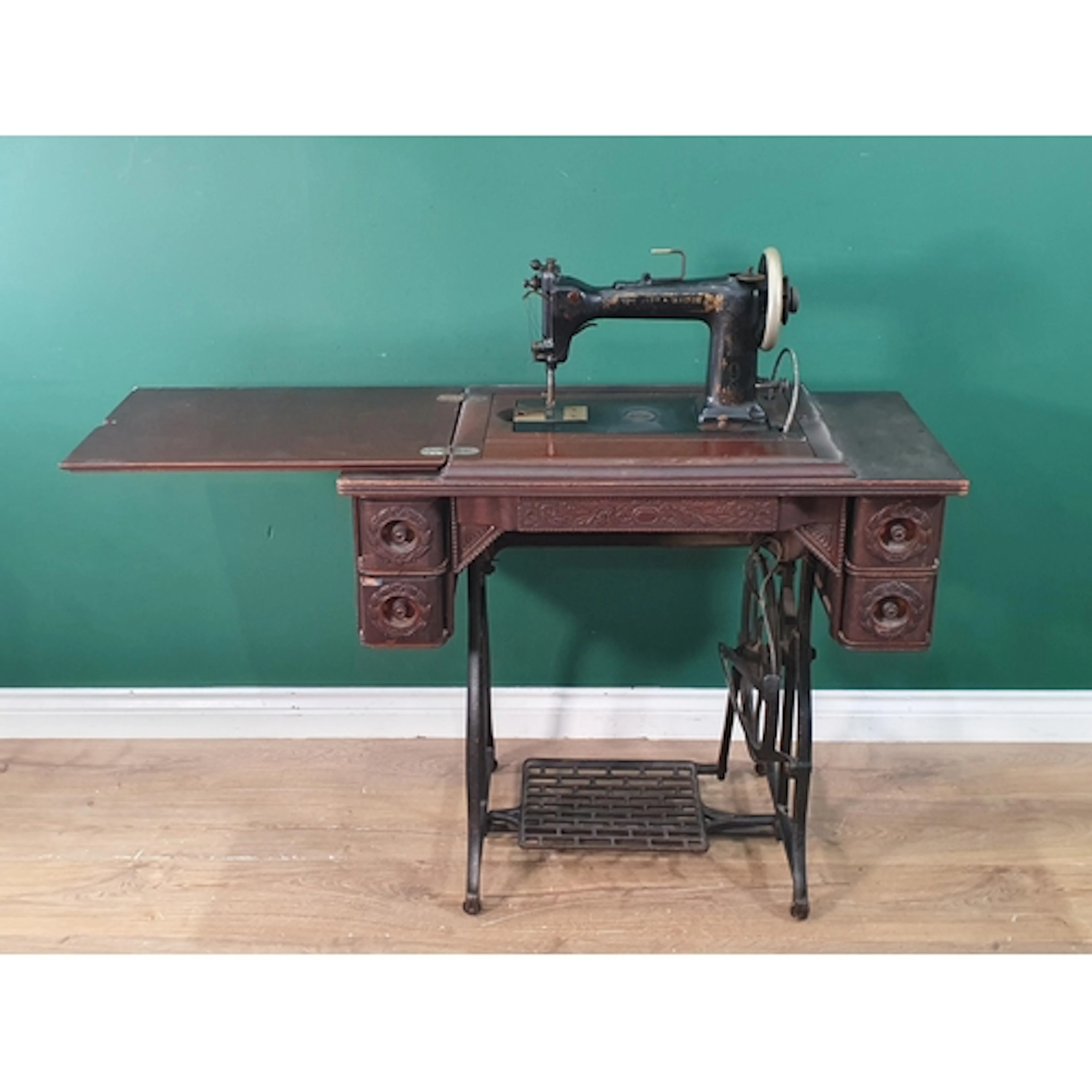 A Wheeler & Wilson Tredle Sewing Machine in carved cabinet, ...