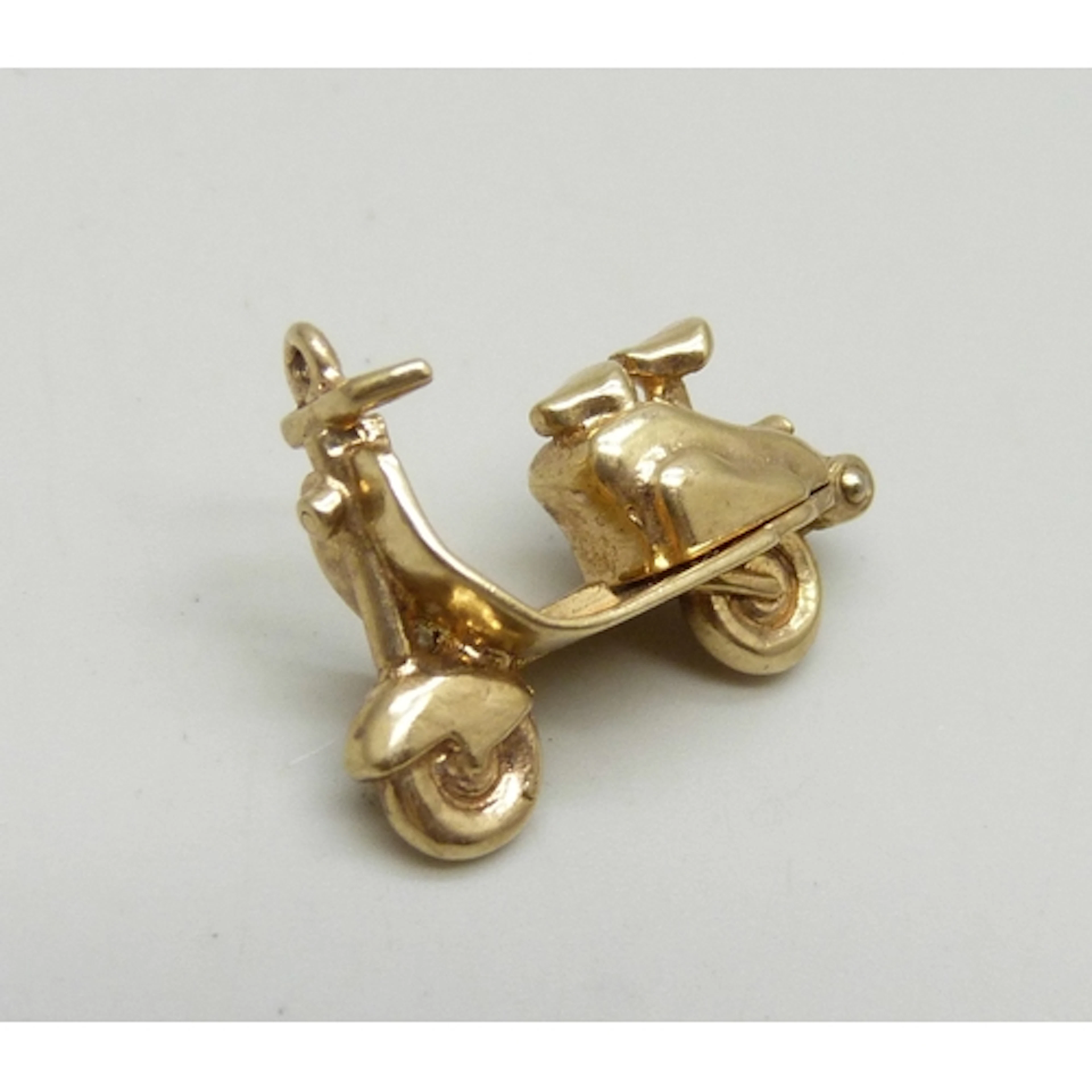 A 9ct gold charm in the form of a scooter or moped, the back...