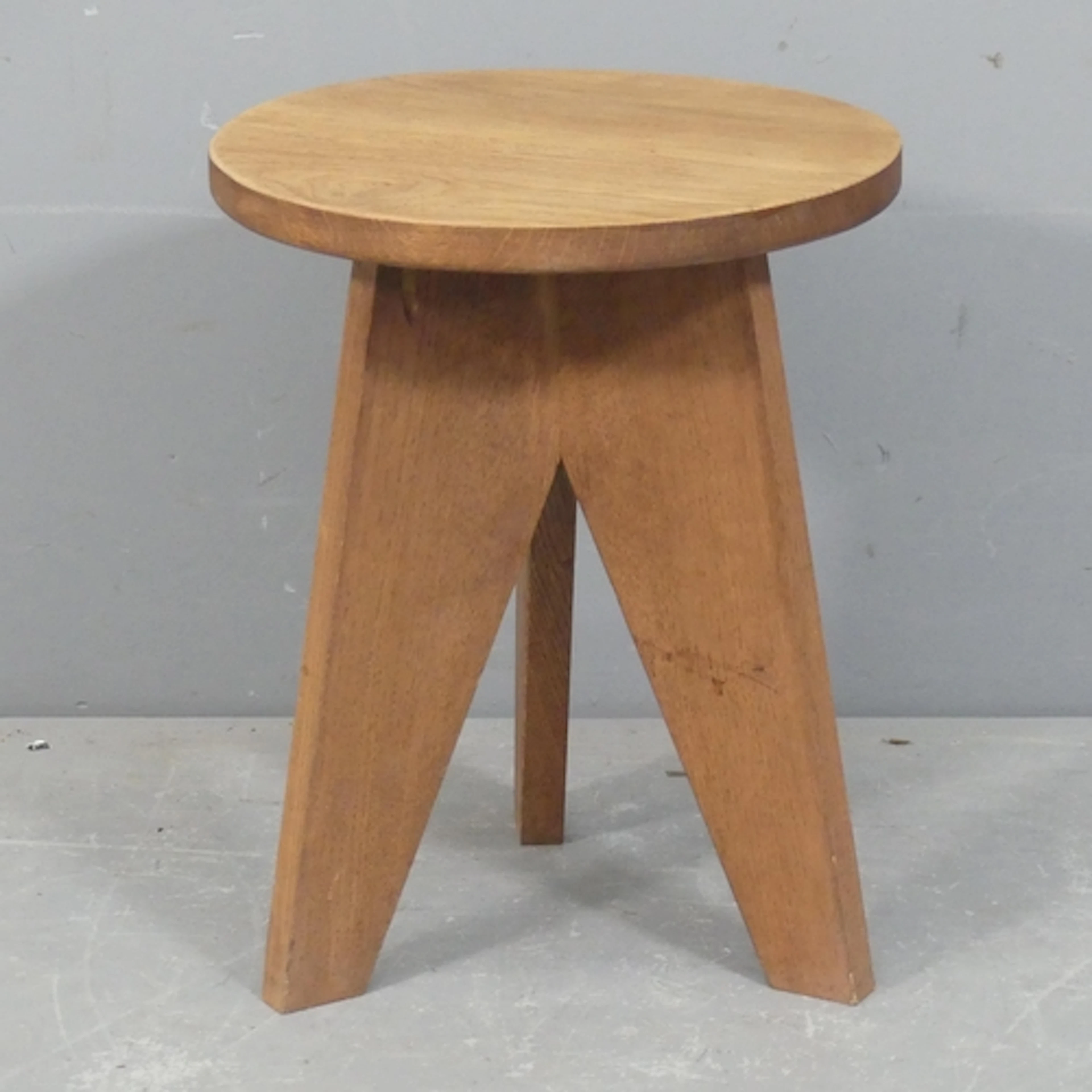 A French mid-century oak low stool in the manner of Jean Pro...