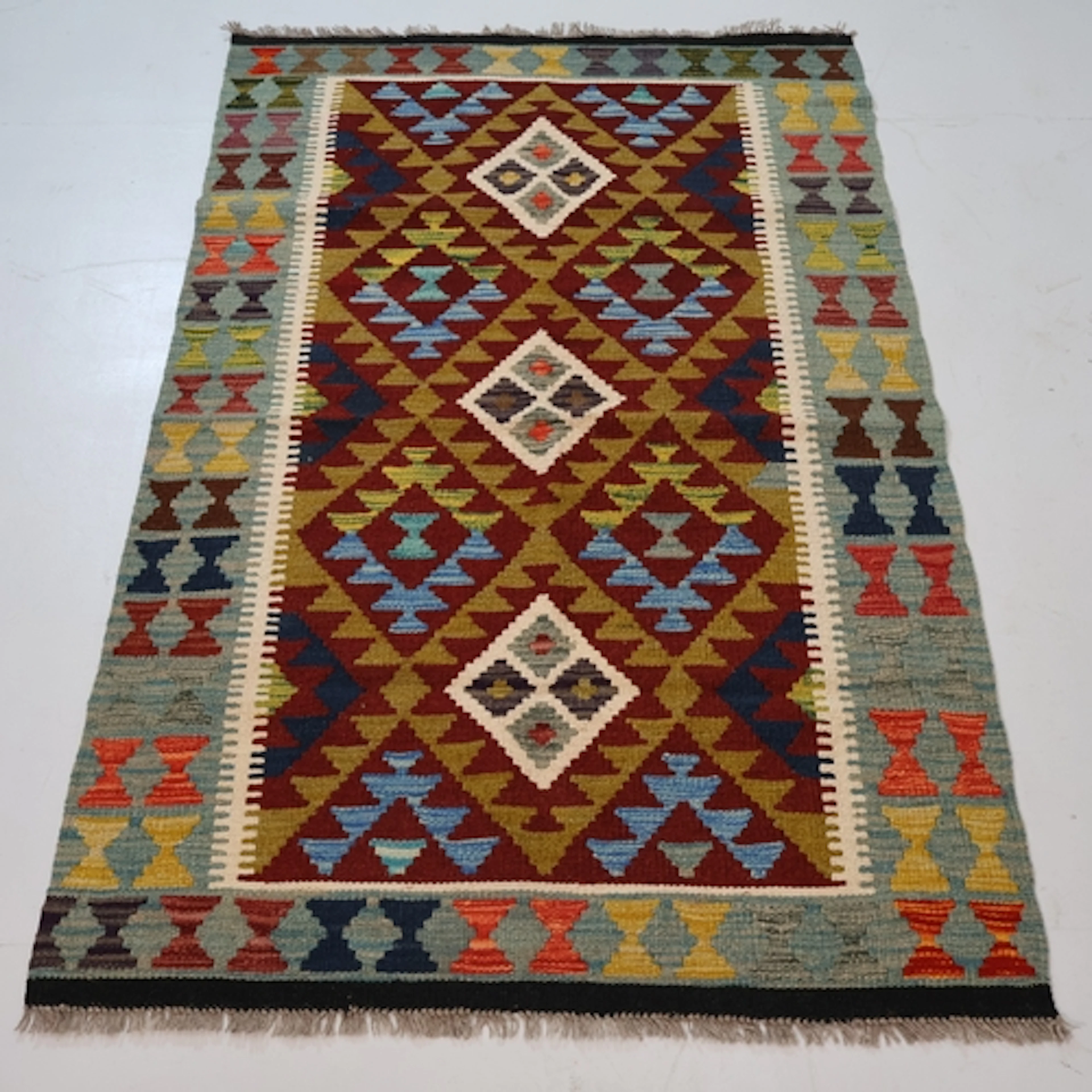 A green ground and bordered maimana kilim rug, L150cm, W97cm...