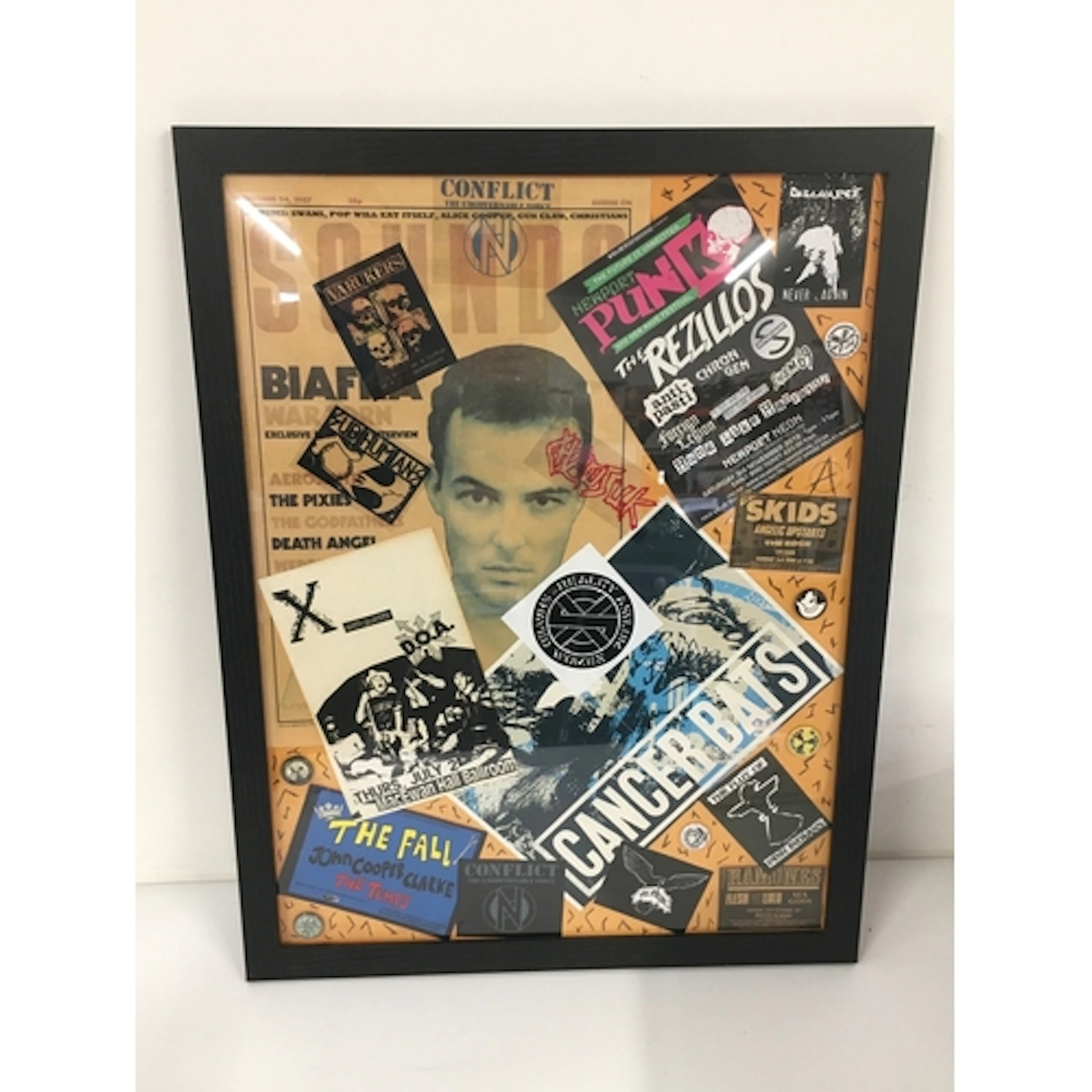 A framed display of punk and indie flyers, stickers, badges ...
