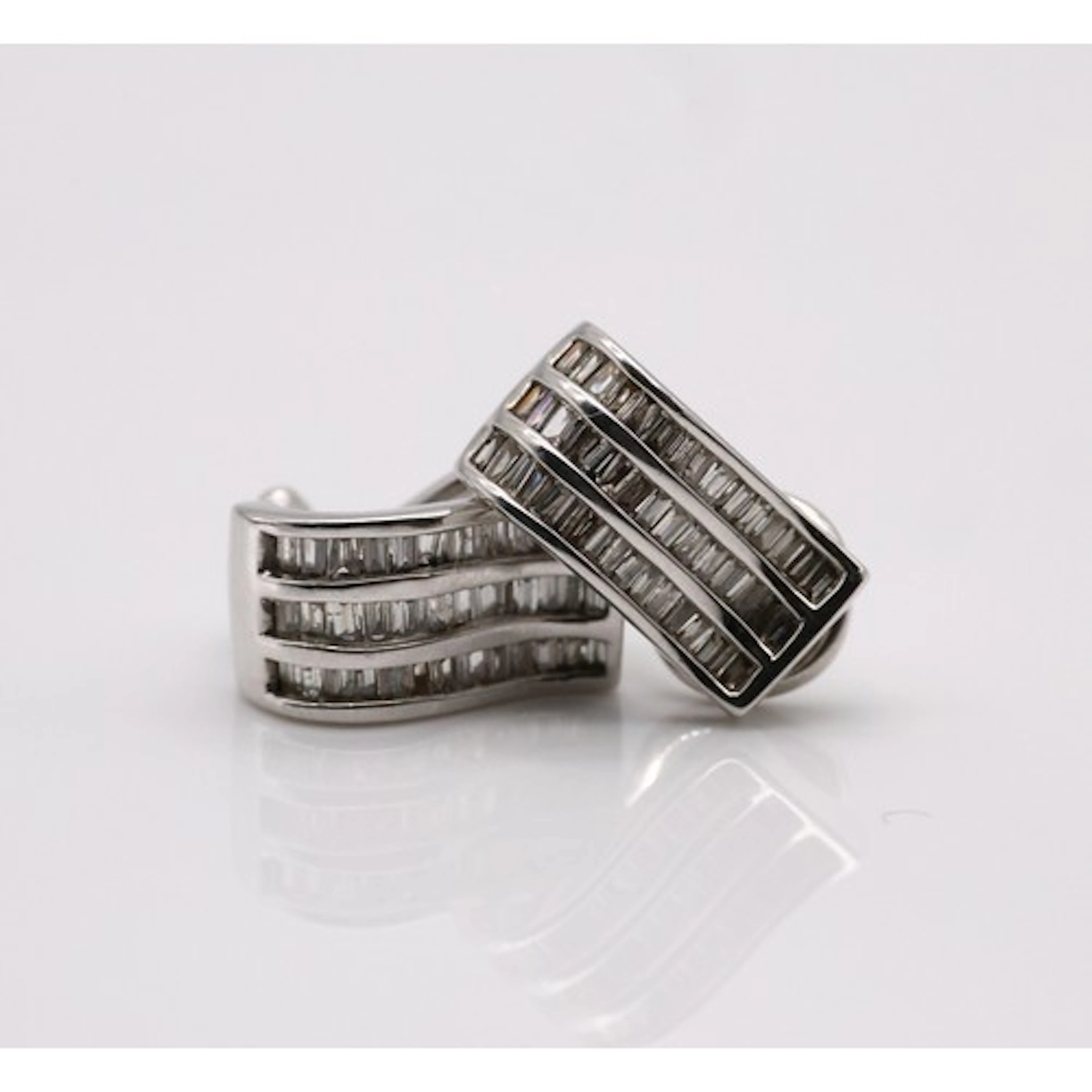 A pair of diamond earrings, each composed of three rows of c...