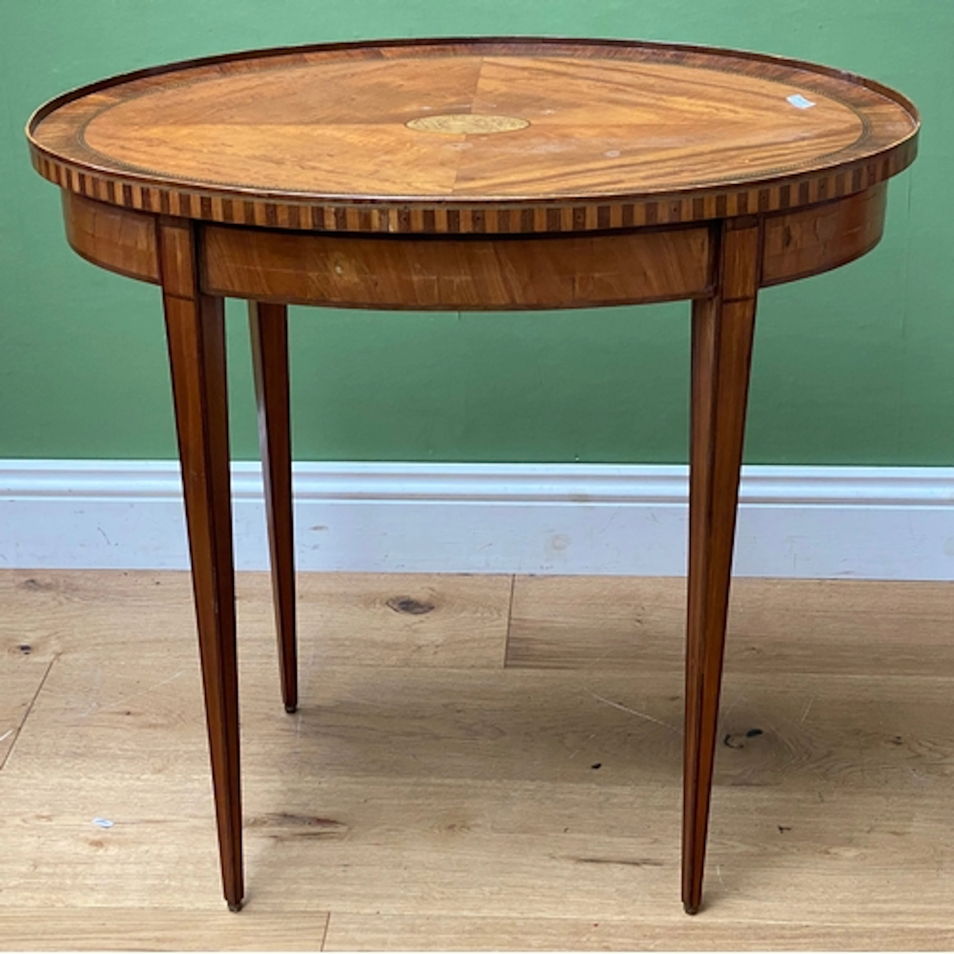 An inlaid oval centre table, quarter veneered top with centr...
