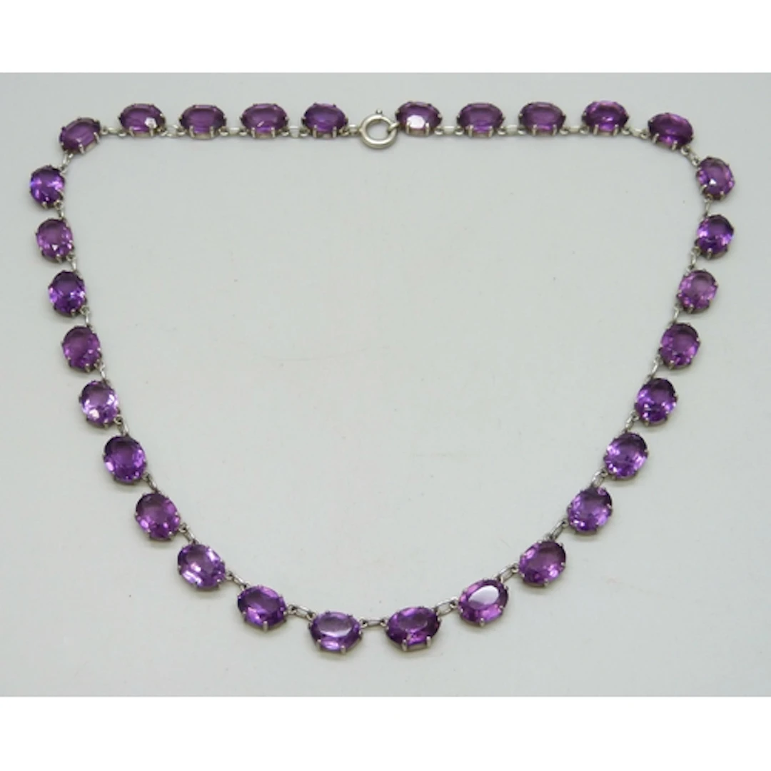 A circa 1900 white metal riviera necklace set with purple pa...