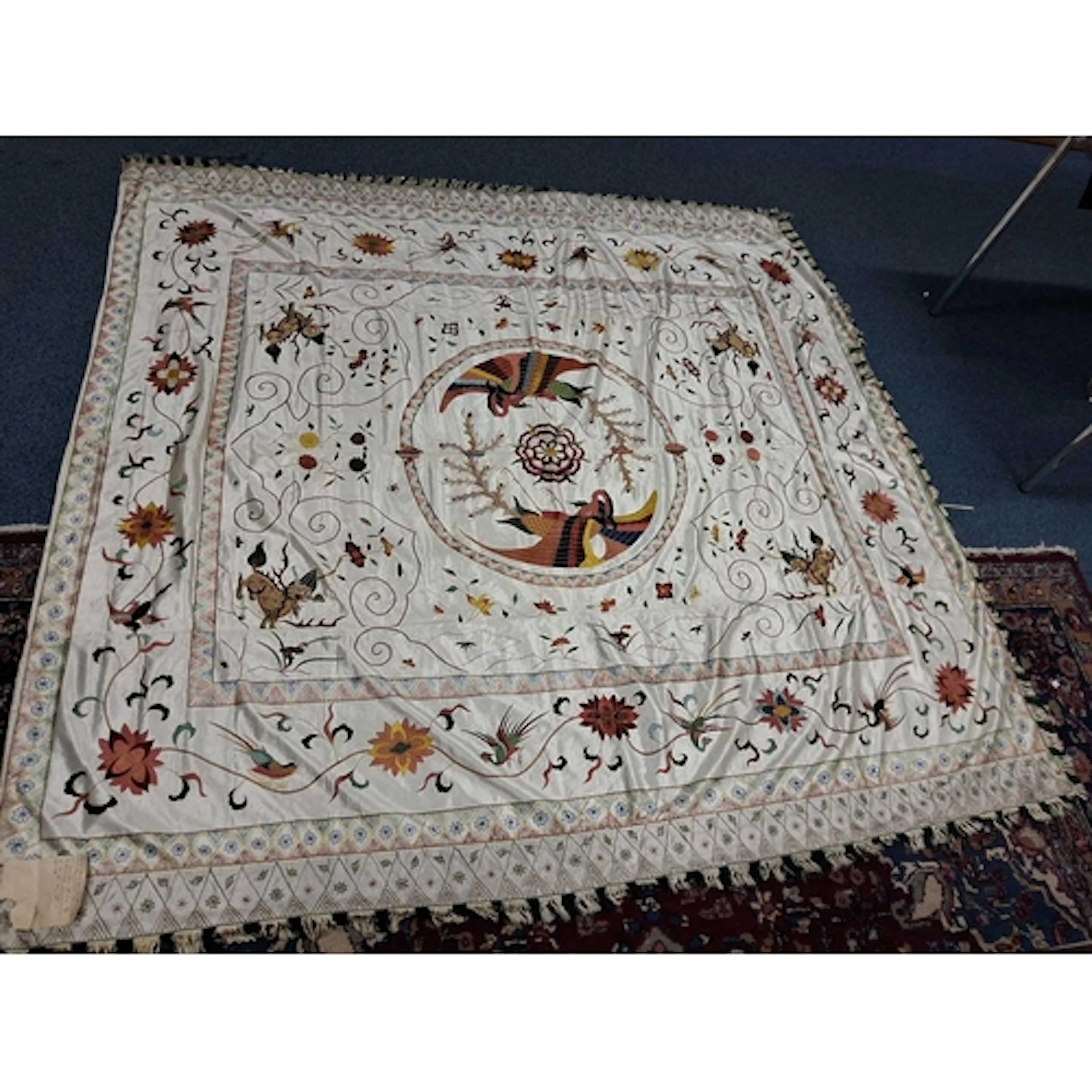 A SILK THROW, hand embroidered with Chinese motifs including...