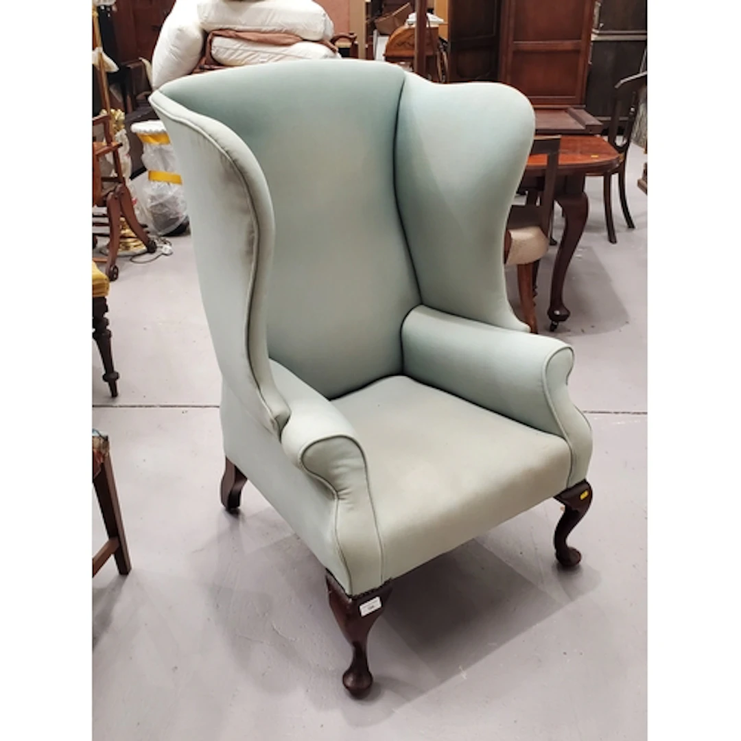 A Georgian style green upholstered wing Armchair on cabriole...