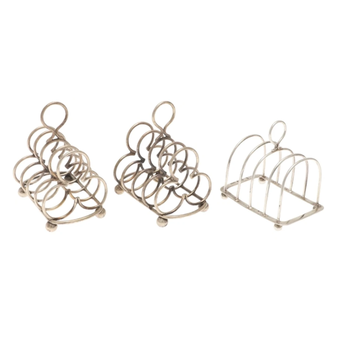 A PAIR OF EDWARDIAN SILVER FOUR PLACE TOAST RACKS AND ANOTHE...