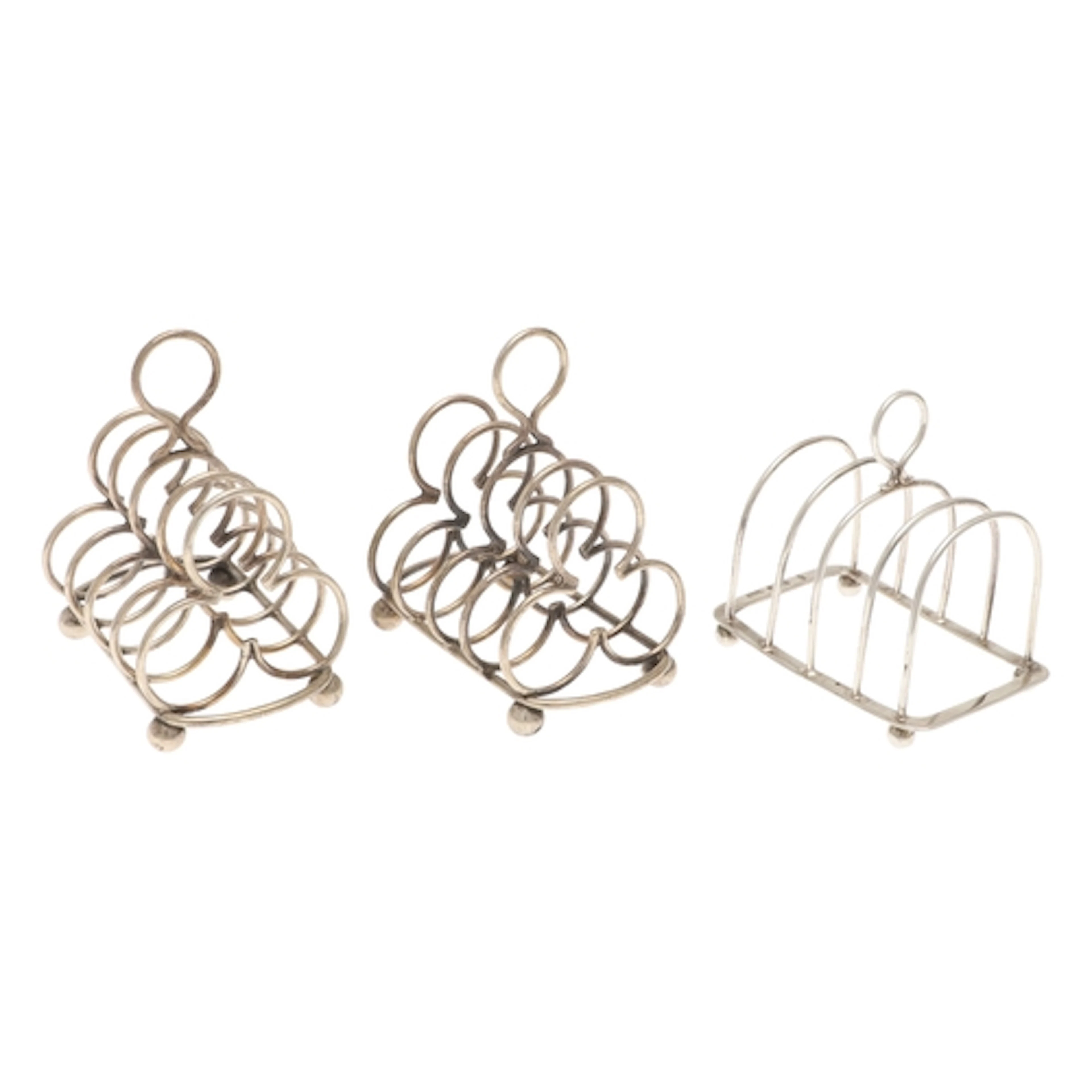 A PAIR OF EDWARDIAN SILVER FOUR PLACE TOAST RACKS AND ANOTHE...