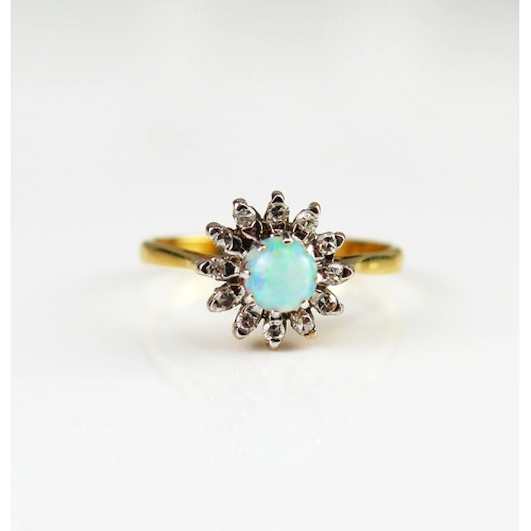 An opal and diamond cluster ring in an 18 carat yellow gold ...