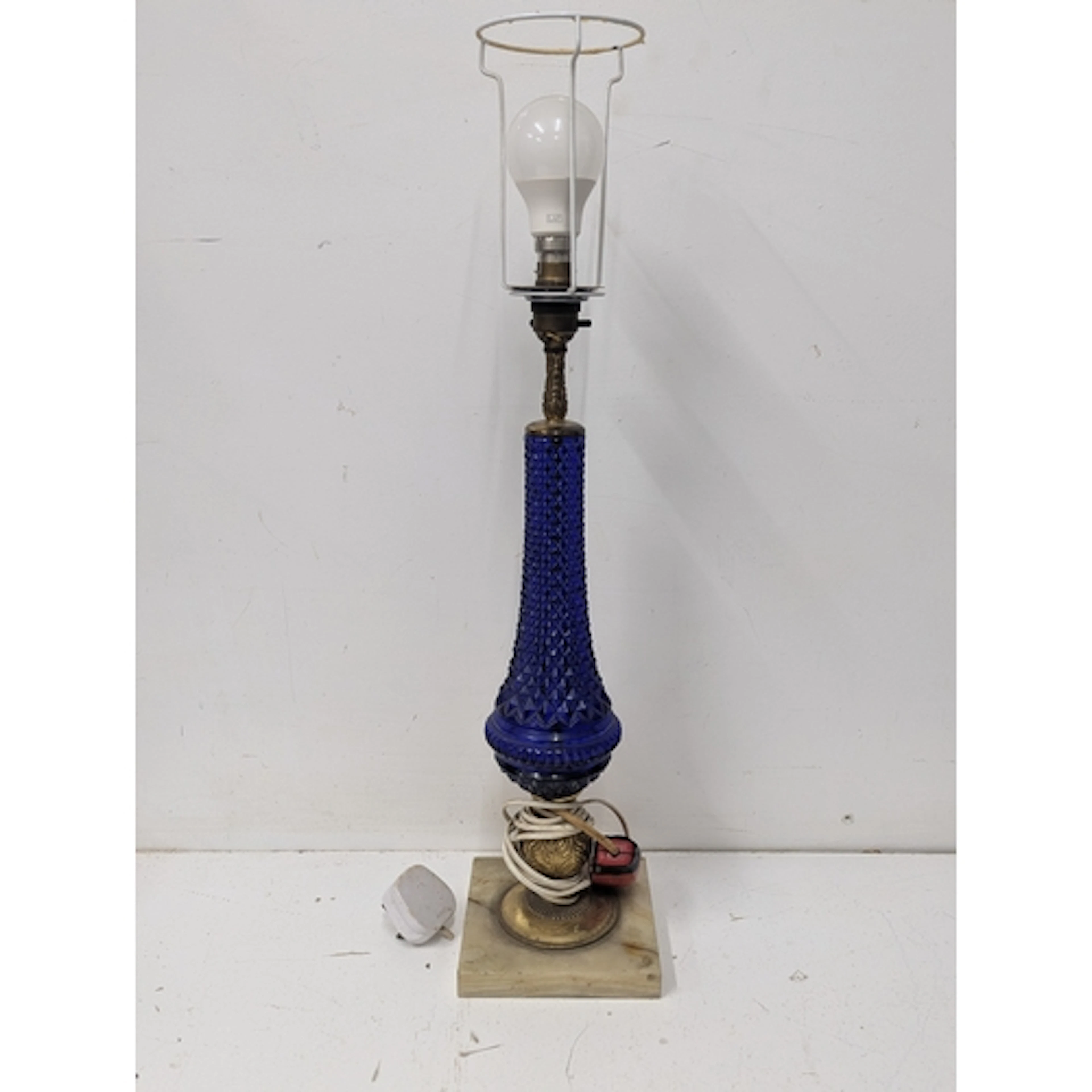 A table lamp featuring a diamond pattern cobalt blue glass b...