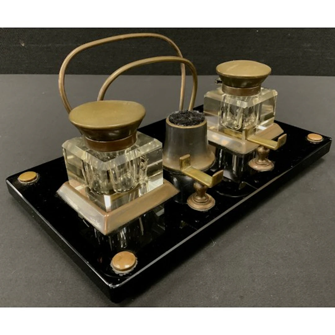 An Art Deco desk inkwell, featuring a glossy black base, bra...